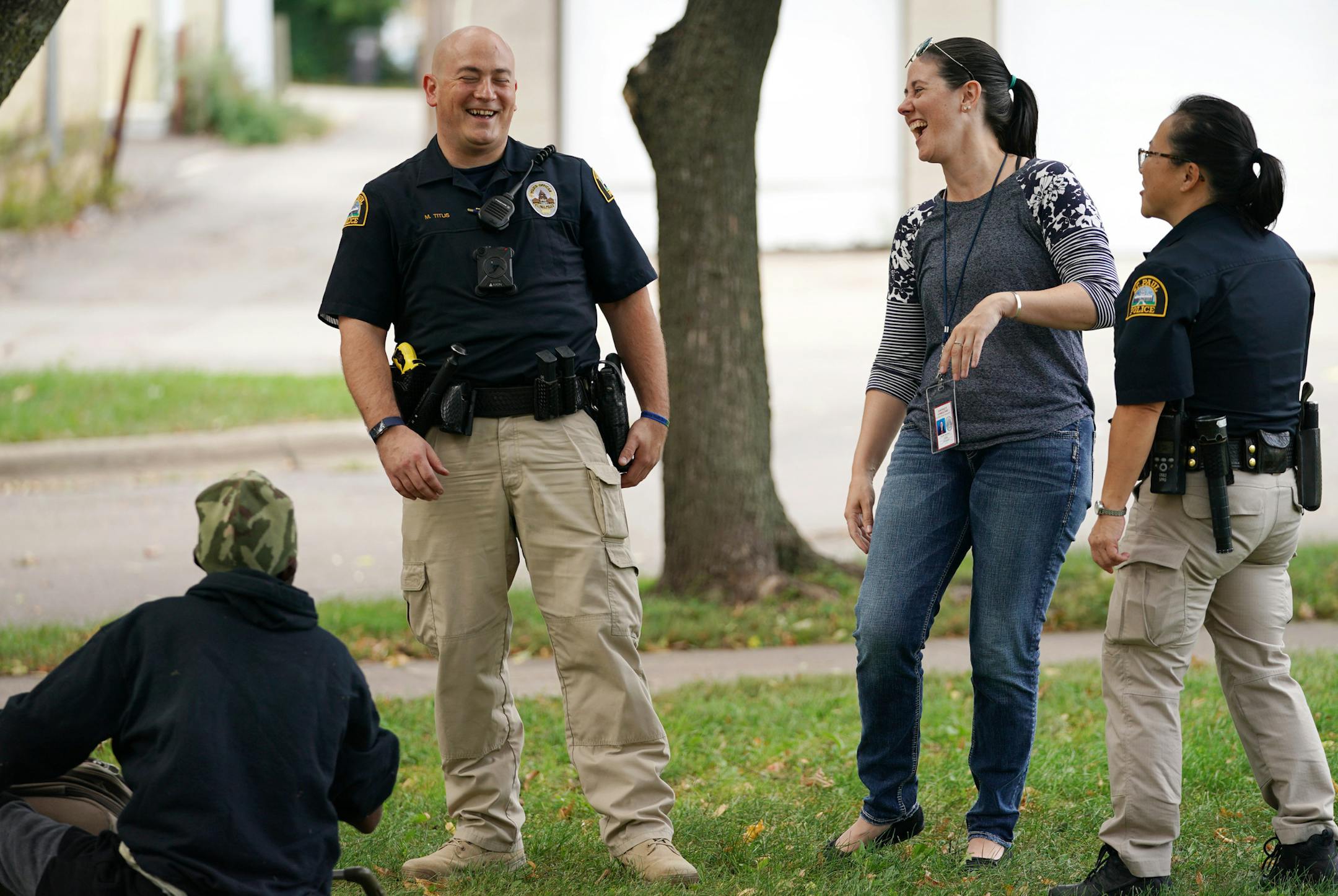 Licensed clinical social worker Kara Haroldson, center, stood with officers Justin Tiffany and Lori Goulet as they checked the well being of a man sleeping in a park.] ANTHONY SOUFFLE • anthony.souffle@startribune.com A pair of social workers from Regions Hospital worked alongside St. Paul police responding to mental health crisis calls Sept. 13, 2018 in St. Paul.