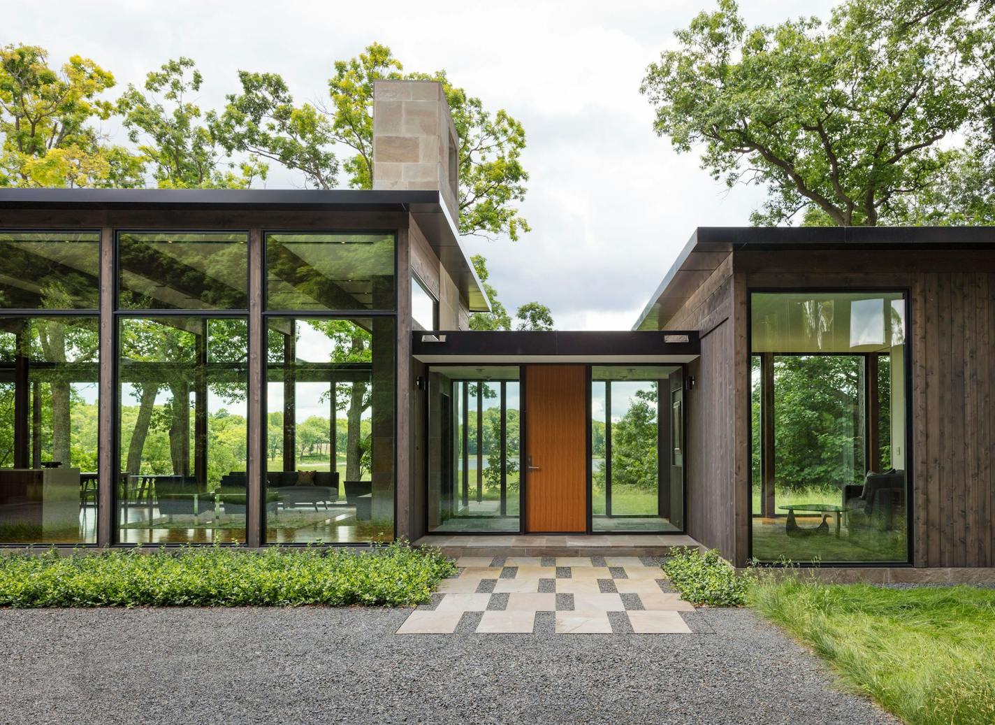 Visitors get a sneak peek of the wetlands and lake before entering the front door. The brown-toned cedar siding blends with the wooded setting.