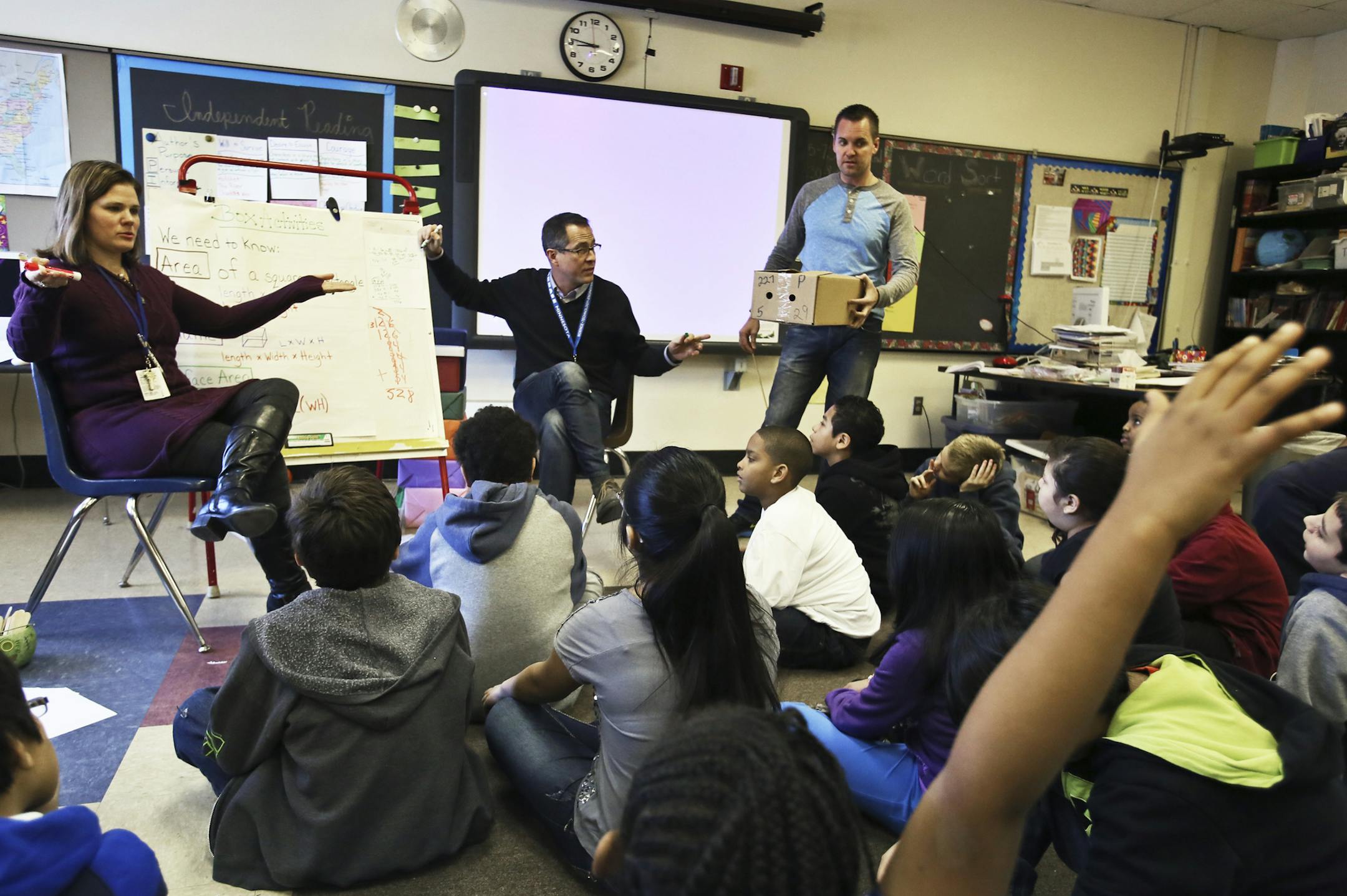 At Pillsbury Elementary School it is becoming more common for teachers and paras to team-teach in classrooms so that often more than one adult is in classrooms -- a model the district plans to put in place in some of its schools. Here, classroom teacher Tara Fagerlee, rear, left to right, associate educator Jeff Rajacich and special education teacher Ben Goltz work together to teach math and the principles of calculating the area of rectangles Tuesday, Dec. 10, 2013 in Fagerlee's 5th grade class