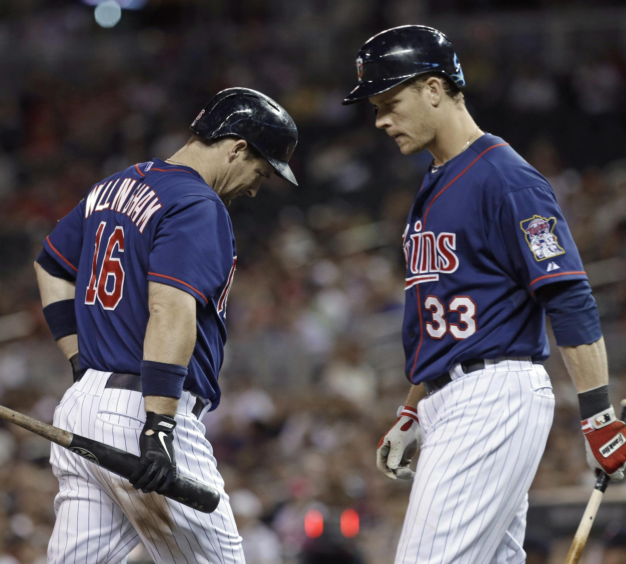 Minnesota Twins' Josh Willingham, left, passes the next batter, Justin Morneau, after striking out in the eighth inning of a baseball game, Friday, May 31, 2013, in Minneapolis. Both Willingham and Morneau went hitless as the Seattle Mariners shut out the Twins 3-0. (AP Photo/Jim Mone)