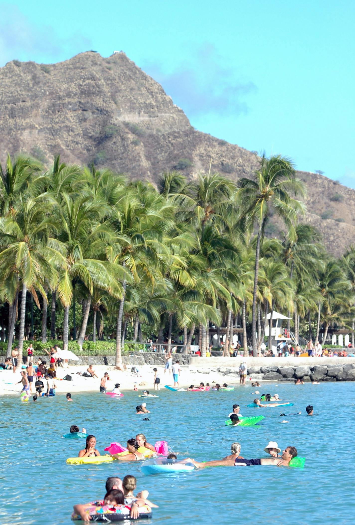 Tourists stay cool in the waters of Waikiki Beach near Diamond Head Mountain in Honolulu.