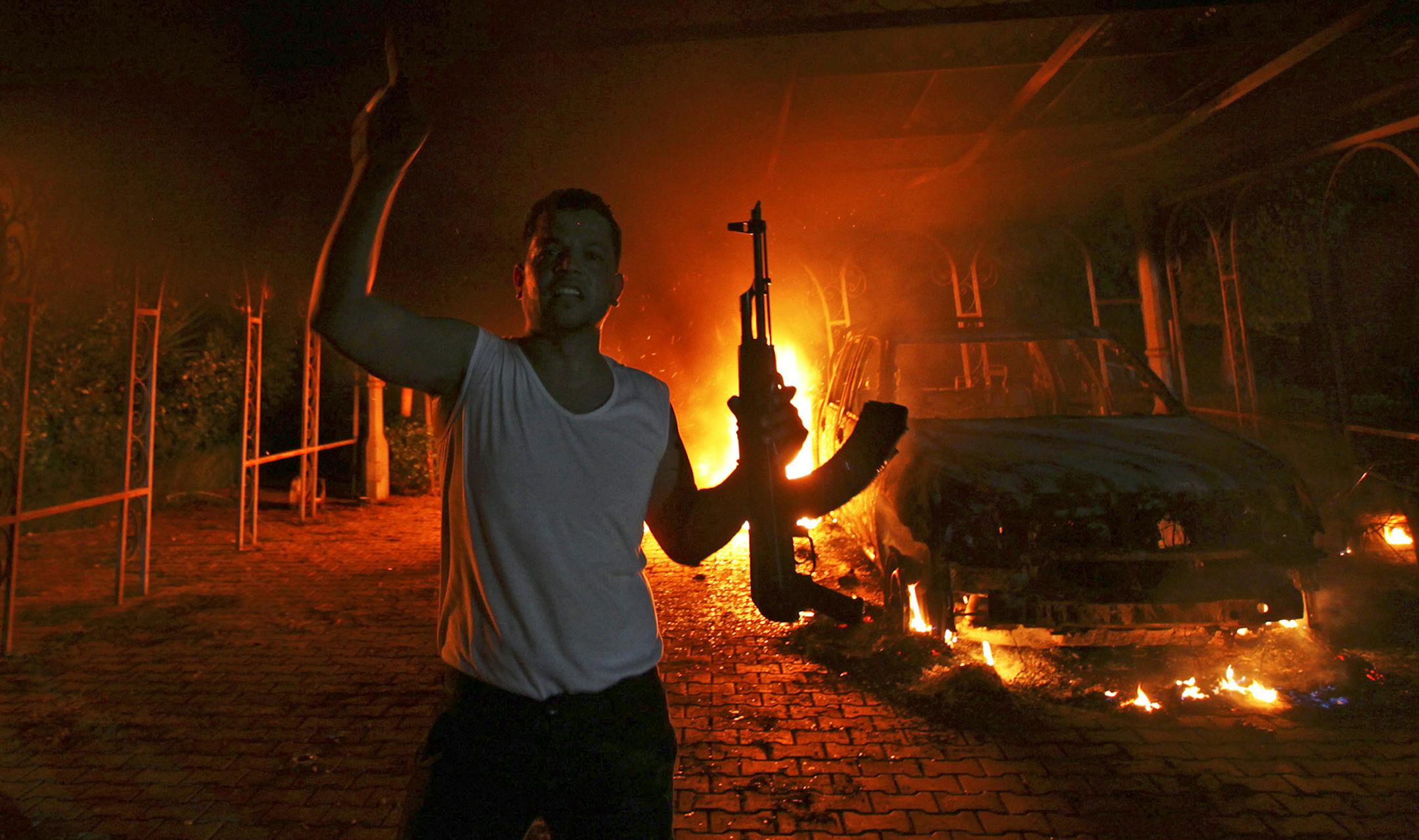 A protester reacts as the U.S. Consulate in Benghazi is seen in flames during an attack on September 11, 2012.