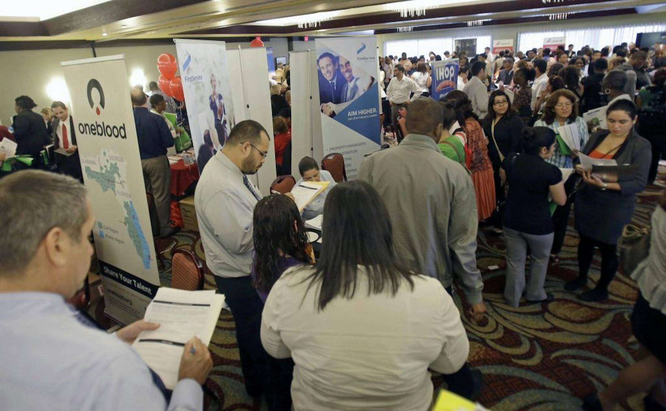 In this Wednesday, Aug. 14, 2013 photo, job seekers check out companies at a job fair in Miami Lakes, Fla. The Labor Department reports the number of Americans who applied for unemployment benefits for the first week of September on Thursday, Sept. 5, 2013.