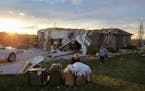 Two women help carry a friend's belongings out of their damaged home after a tornado passed through the area in Bennington, Neb., Friday, April 26, 20