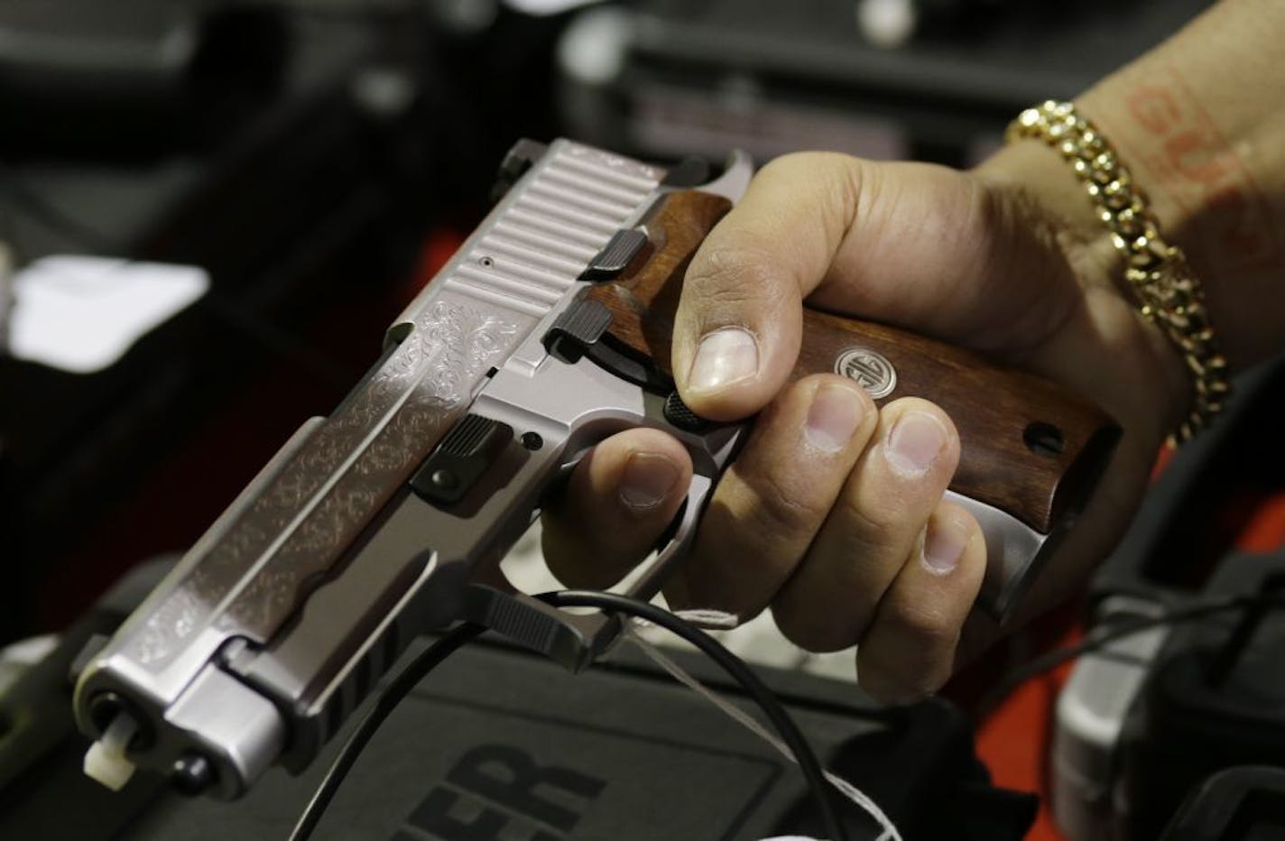 A customer looks at a SIG Sauer hand gun at a gun show held by Florida Gun Shows, Saturday, Jan. 9, 2016, in Miami. President Barack Obama announced proposals this week to tighten firearms sales through executive action.