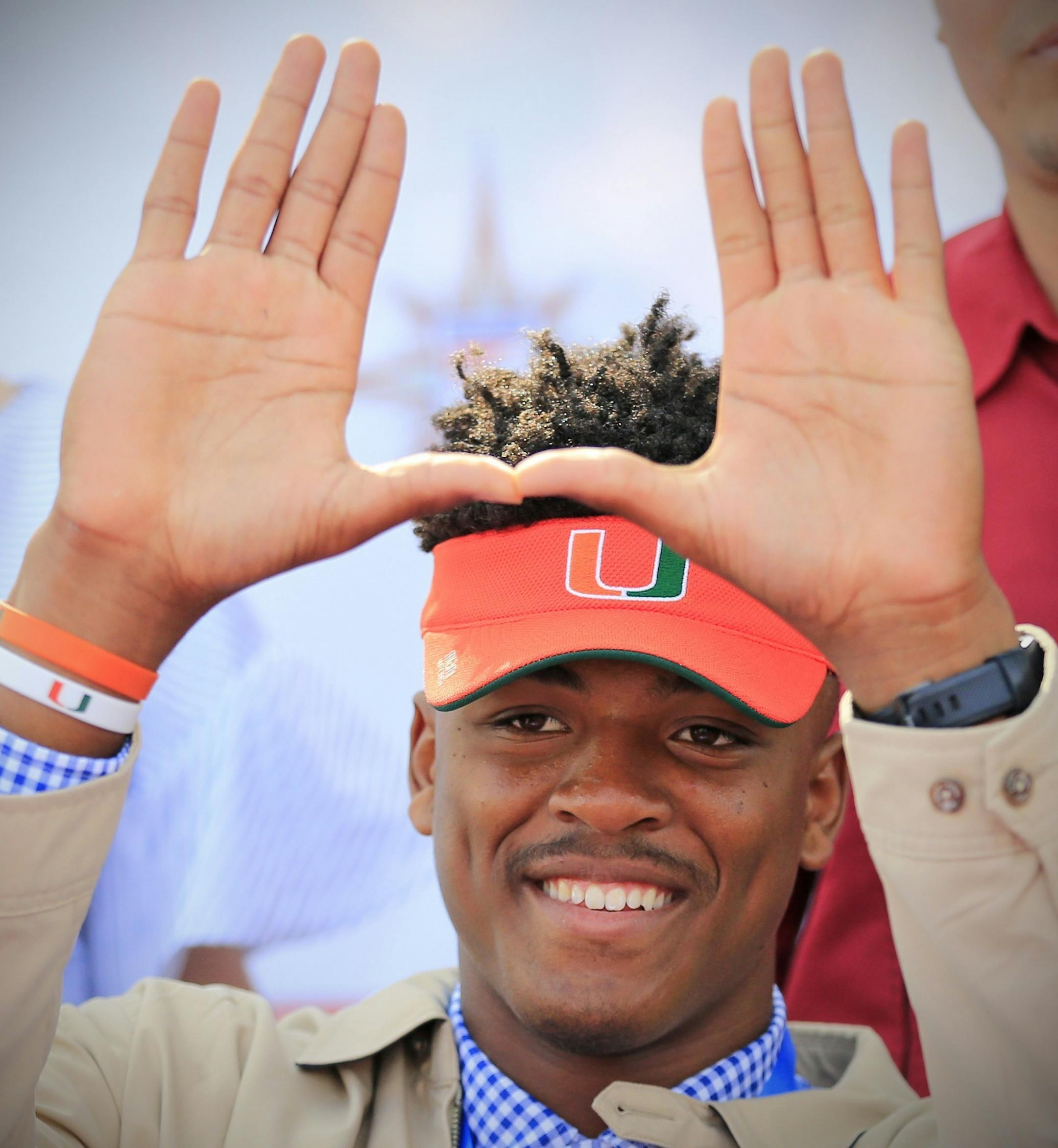 Gregory Rousseau, a Champagnat Catholic High School football player, makes a "U" gesture announcing his intentions to attend the University of Miami during the NCAA college football early signing period, Wednesday, Dec. 20, 2017, in Sunrise, Fla. (Al Diaz/Miami Herald via AP)