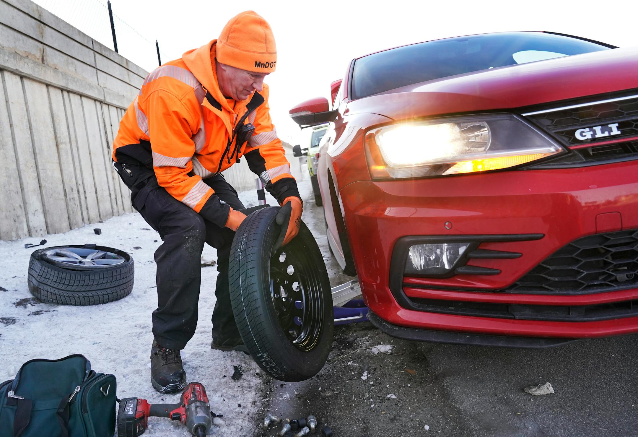 Mike Ahlman, MnDOT's Freeway Incident Response Safety Team driver, assists a stranded physician along I-94 that had a flat tire and was running late for their morning appointments Tuesday, Feb. 21, 2023 in Minneapolis, Minn. When motorists break down, it's MnDOT's FIRST units to the rescue. For 30 years, the yellow trucks once known as the "Highway Helper" had jumped dead batteries, fixed flat tires and even provided gas to motorists who have run out and get stranded on the road.**Mike Ahlman, cq