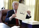 President Donald Trump displays the $1.5 trillion tax overhaul package he had just signed, Friday, Dec. 22, 2017, in the Oval Office of the White Hous