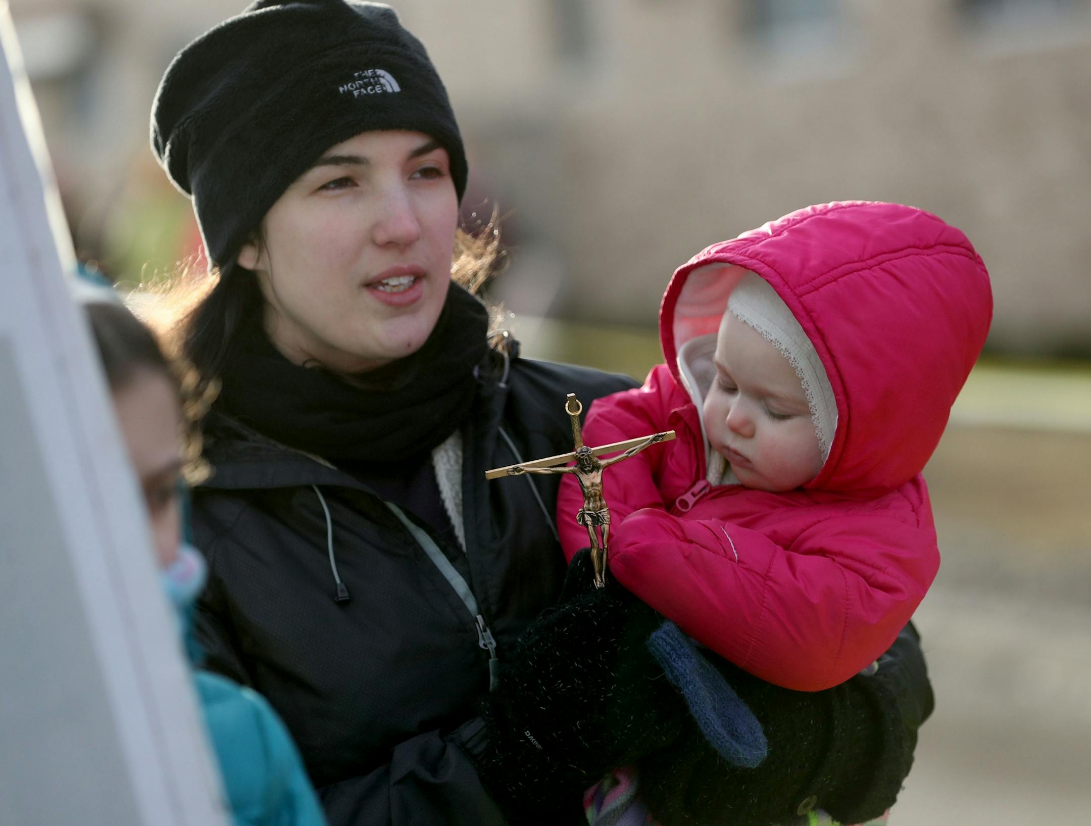 SamDefend Planned Parenthood and Pro-Life Action Ministries had dueling protests Saturday, Feb. 11, 2017, at the Planned Parenthood center in St. Paul, MN. Here, Jacquelyn Willodson of White Bear Lake, a supporter of Pro-Life Action Ministries, held one her three children and a crucifix as she prayed with her husband Samuel, not pictured. Jacquelyn said she volunteered for Planned Parenthood in 2013 and saw how they operated before the family chose to convert to Catholicism.