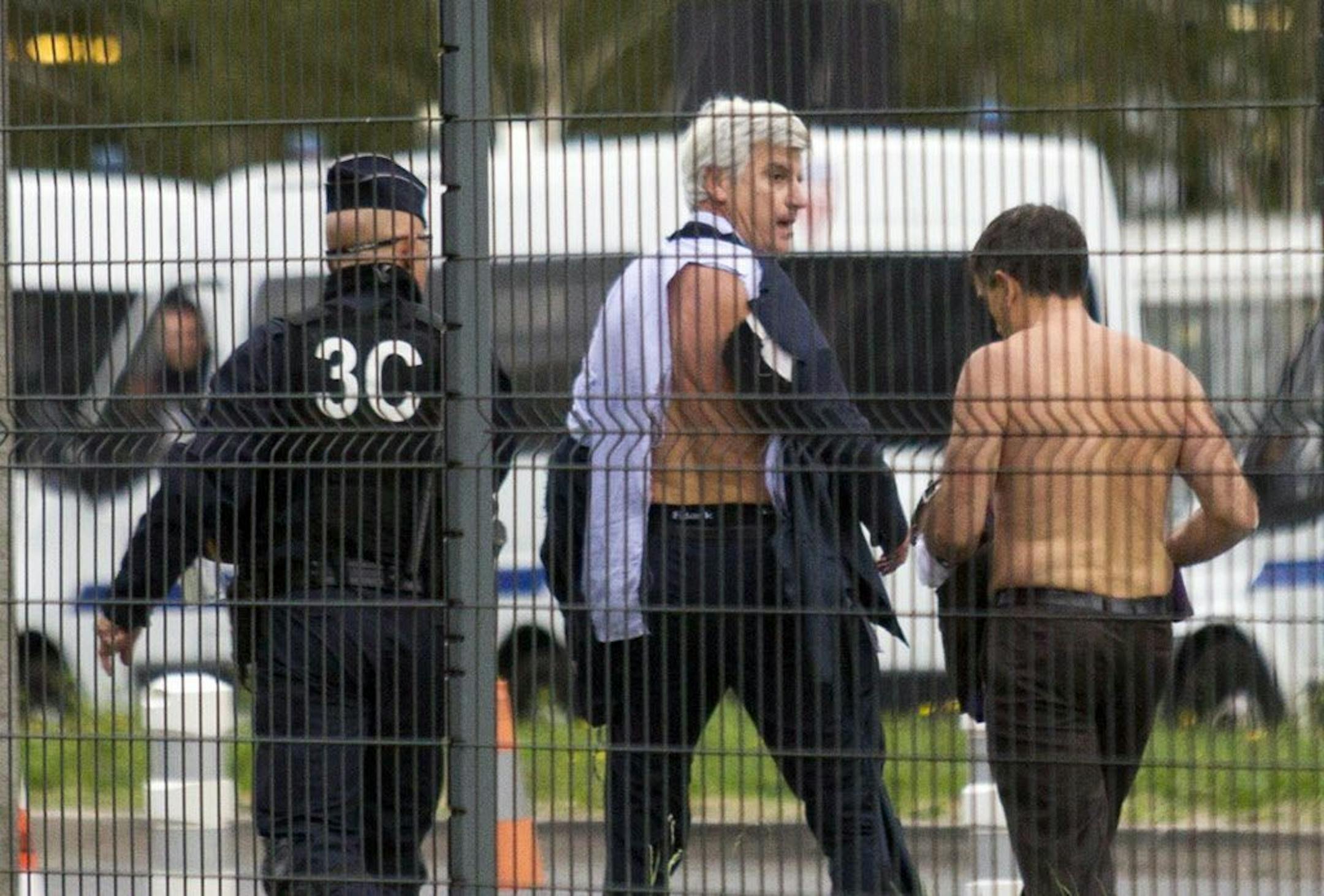 Air France director of Human Ressources, Xavier Broseta, right, and Air France assistant director long-haul flight, Pierre Plissonnier, center, are protected by a police officer as they flee the company headquarters at Roissy Airport, north of Paris, after scuffles with union activist, Monday, Oct. 5, 2015. Union activists protesting proposed layoffs at Air France stormed the headquarters during a meeting about the job cuts, zeroing in on two managers who had their shirts torn from their bodies,