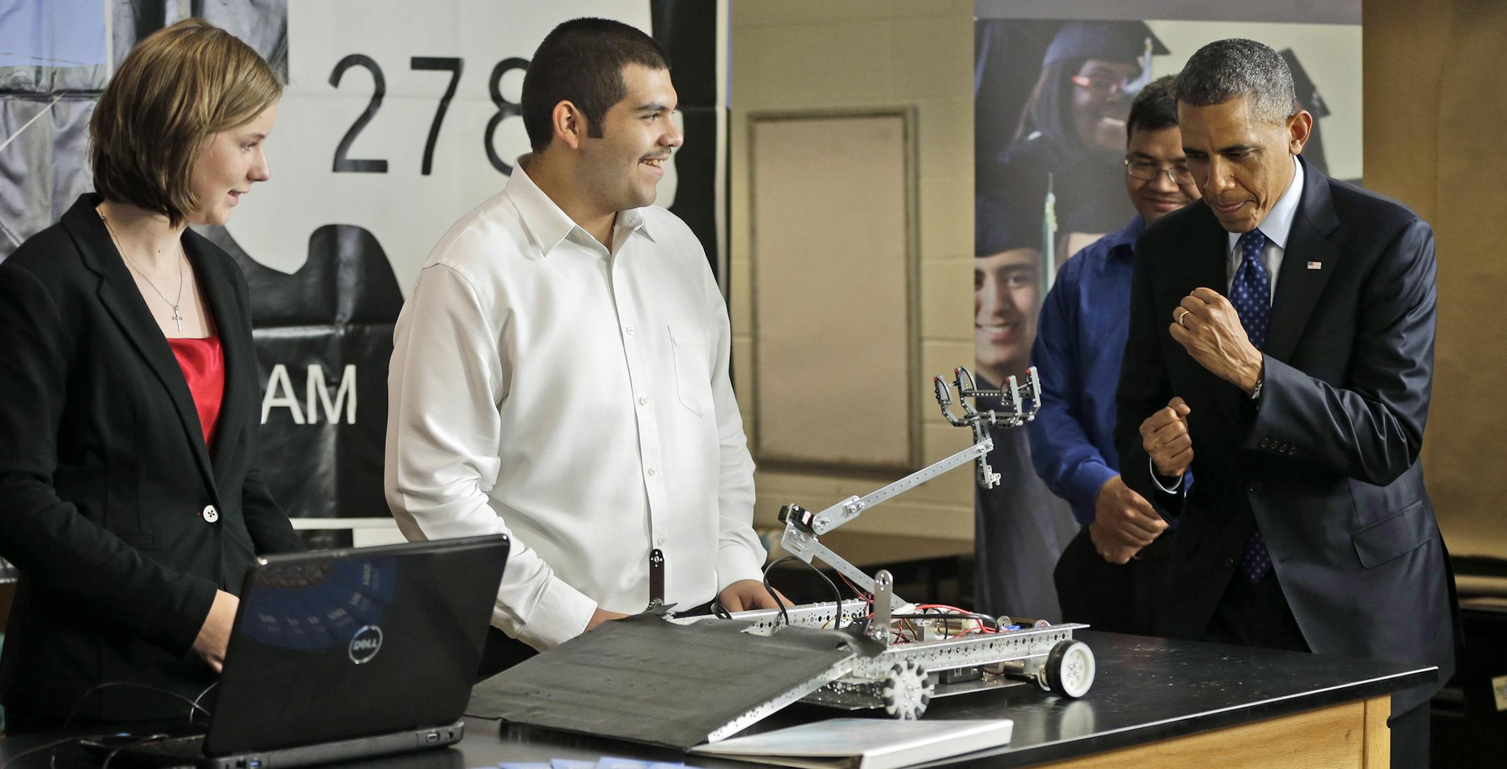 President Barack Obama, right, throws his fists up as a robotic vehicle, controlled by students Hannah Hutton, left, and Patrick Sandoval, center, moves towards him during a visits to Manor New Technology High School, Thursday, May 9, 2013 in Manor, Texas. (AP Photo/Pablo Martinez Monsivais)