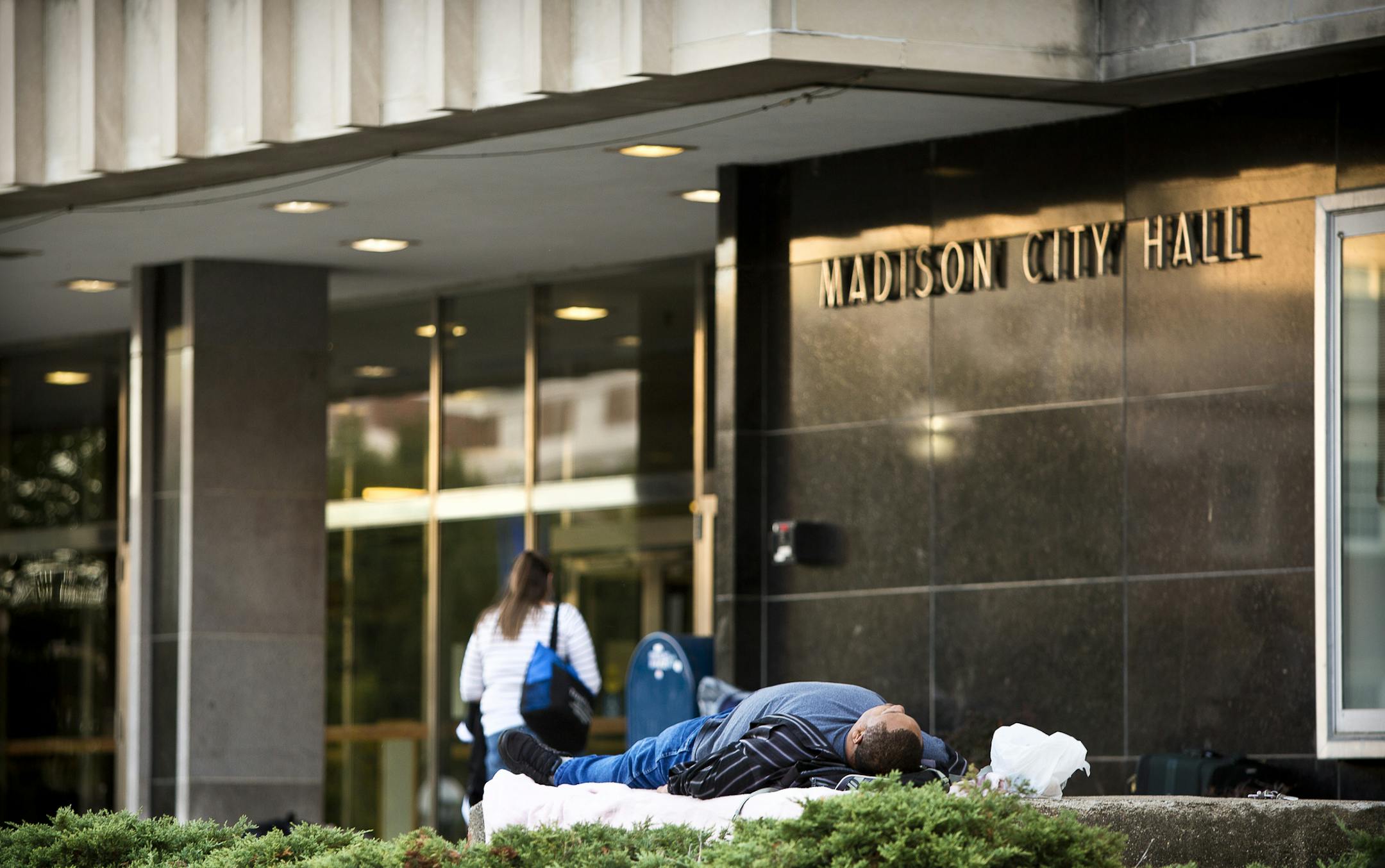 A homeless man rests in front of the City County Building in downtown Madison, Wis., Sept. 14, 2015. Madisonís Democratic mayor, Paul Soglin, successfully pushed for a measure last month that will ban anyone from sleeping at night outside City Hall, shutting down what has become Madisonís most public de facto homeless shelter. (Ben Brewer/The New York Times)