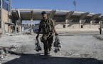 A member of U.S.-backed Syrian Democratic Forces (SDF) carries explosives at a stadium that was the site of Islamic State fighters' last stand last we