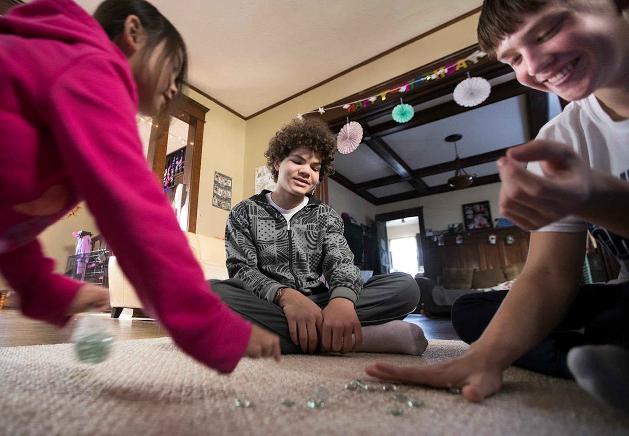 Minnehaha Academy students Peter Shaffer, from right, 14, and Daniel Rose, 14, play a Hmong marble game with Diav Vue, 7, while staying at her mom's home in St. Paul. ] LEILA NAVIDI ï leila.navidi@startribune.com BACKGROUND INFORMATION: in St Paul on Wednesday, March 15, 2017. City Stay is an opportunity for Minnesota high school students to do home stays at the homes of other local residents. The cultural exchange program fosters new relationships among Minnesota's European, Latin American, Som