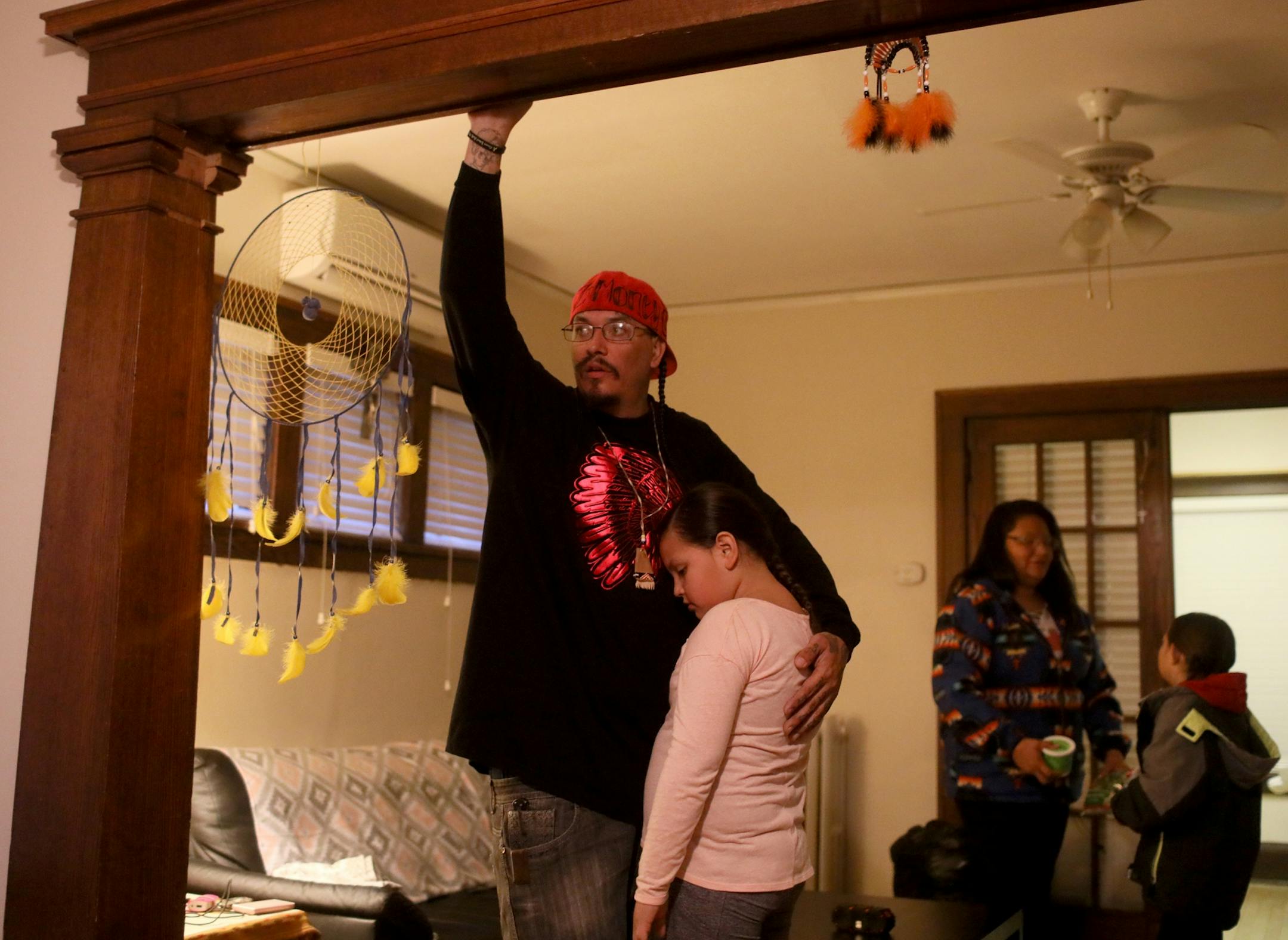 This week, after months of living at a crowded homeless camp, Mike and Ellen Eagletail and their three children finally moved into a place of their own. They are among a small but growing number of people at a south Minneapolis homeless camp who are starting to find housing. Here, Mike hugs his daughter Rolanda, 8, while Ellen talks to Lakota, 7, in the living room of their new apartment before they took their children to school Thursday, Oct. 25, 2018, in Minneapolis, MN.