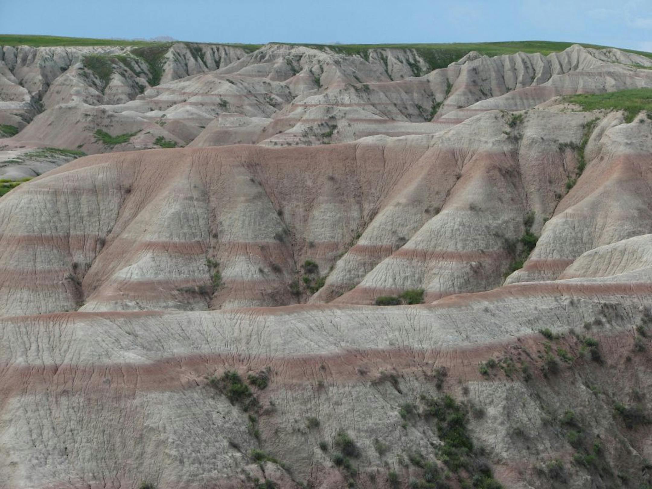 Wide red and brown stripes point to the passage of time in the Badlands National Park of South Dakota, created by rising mountains, erosion, and an extinct inland sea that once stretched from the Gulf of Mexico to Alaska.