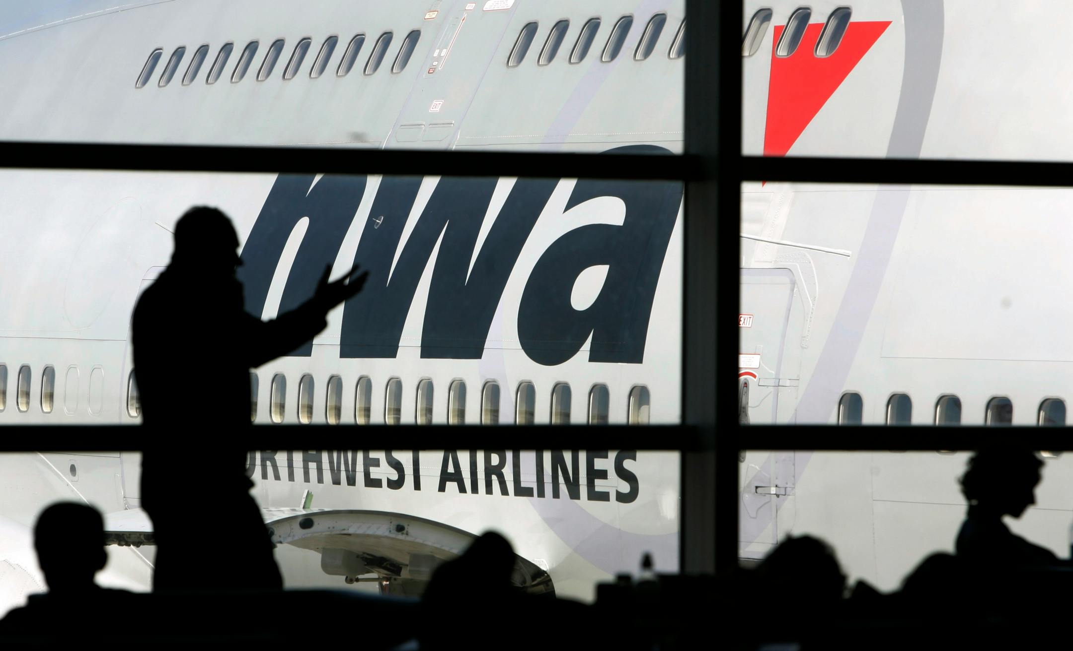 A Northwest plane is seen parked as travelers wait for their flight Tuesday, April 15, 2008 at Detroit Metropolitan Airport in Detroit. Getting hitched may be the right move for Delta and Northwest. But for beleaguered air travelers, it could usher in an era of fewer flights, more confusion at the airport and even more crowded planes.