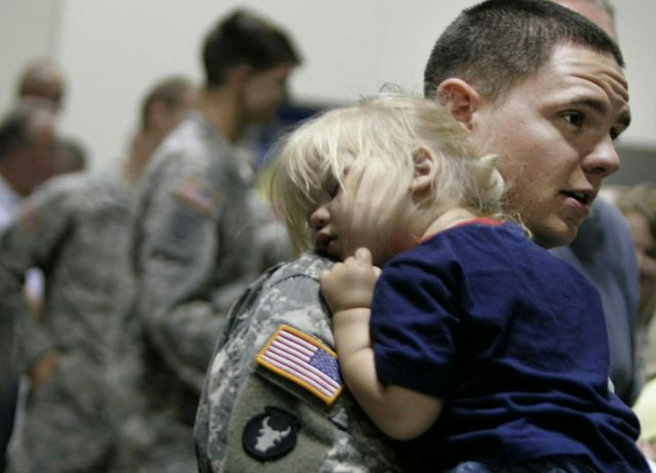 Spc. James Riely of St. Cloud, holds his sleeping daughter Jade, 2, prior to the start of the official welcome home ceremony for the Minnestoa National Guard 34th Combat Aviation Brigade, at the Minneapolis Convention Center. Last year, the 34th deployed in support of Operation Iraqi Freedom. The ceremony included family and friends of the more than 720 soldiers in the unit.