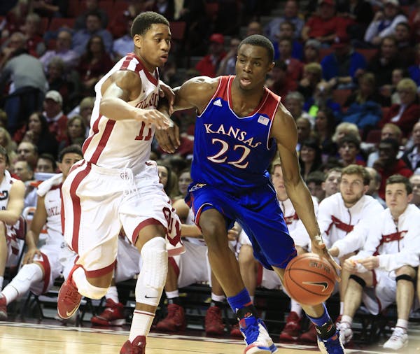 Kansas guard Andrew Wiggins, right, drives around Oklahoma guard Isaiah Cousins, left, during the first half of an NCAA college basketball game in Nor