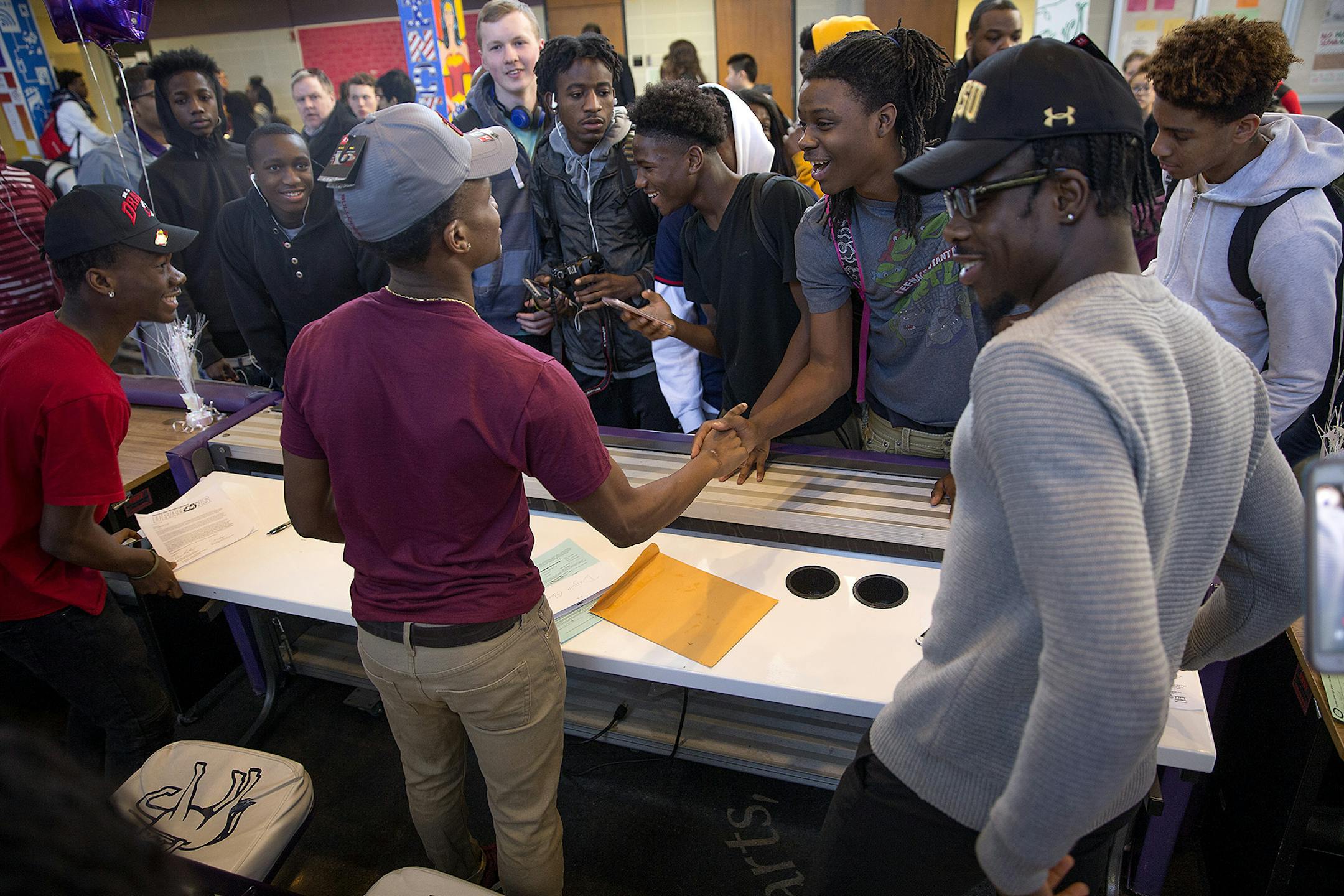 Brooklyn Center football players Junior Kai, left, Dayvia Gbor, center, and Charles Wylie, right were greeted by classmates Wednesday after they signed letter of intent to play in college.