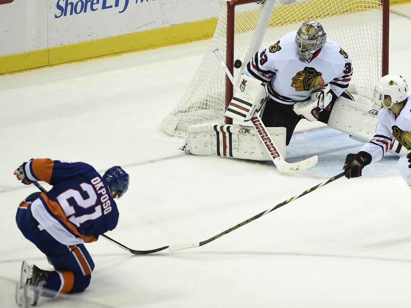 New York Islanders center Brock Nelson (29) and Chicago Blackhawks defenseman Duncan Keith (2) look on as Blackhawks defenseman Niklas Hjalmarsson (4) tries to block Islanders right wing Kyle Okposo's (21) shot against Blackhawks goalie Scott Darling (33) that scored in the third period of an NHL hockey game on Saturday, Dec. 13, 2014, in Uniondale, N.Y. The Islanders won 3-2. (AP Photo/Kathy Kmonicek)