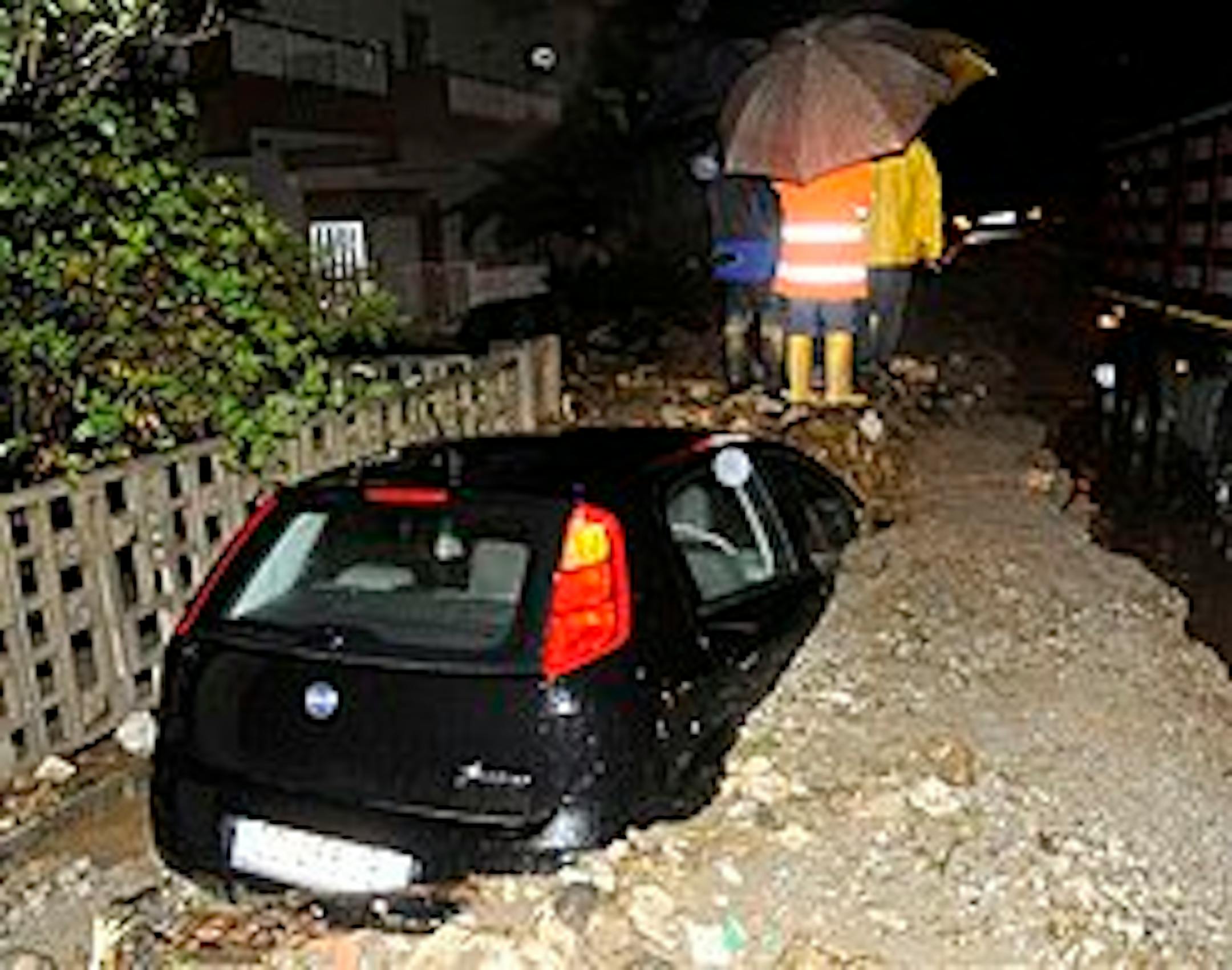 A car is submerged in mud as people shelter themselves under an umbrella early Friday, Oct. 2, 2009 in Messina, southern Italy. At least four people are dead and 20 missing after a river of mud flooded parts of the Sicilian city of Messina as the area was hit by heavy rains. Officials said at least 100 people fled their homes when violent mudslides collapsed several buildings and swept away cars during a rain storm that lasted through Thursday night and early Friday. (AP Photo)