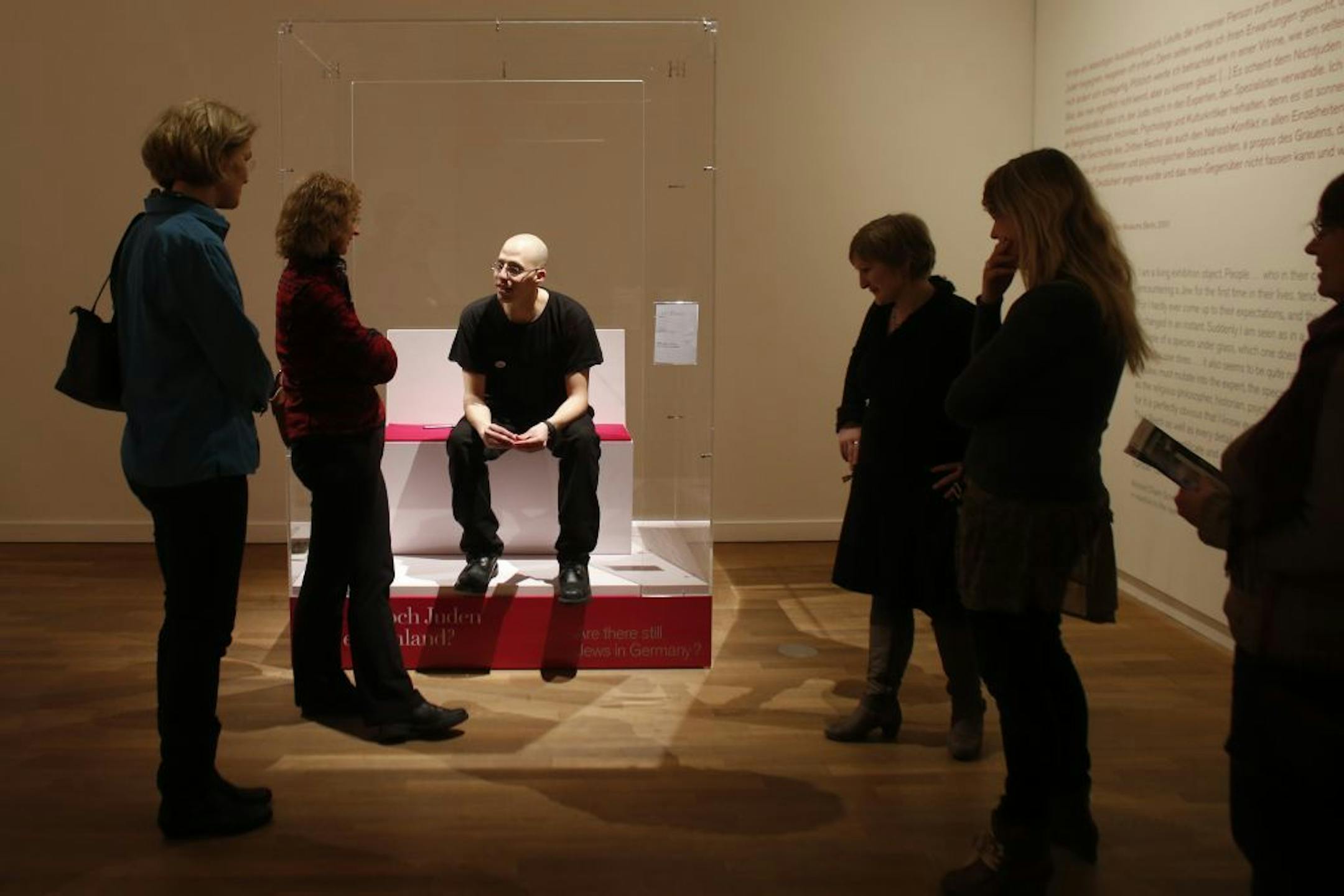 FILE - In this March 22, 2013 file photo, visitors surround Ido Porat, the first person acting as the 'Jew in a glass box', on the first day of the exhibition "The Whole Truth � everything you always wanted to know about Jews" at the Jewish Museum in Berlin. Nearly 70 years after the Holocaust, there is no more sensitive an issue in German life as the role of Jews. With fewer than 200,000 Jews among Germany's 82 million people, few Germans born after World War II know any Jews or much about them