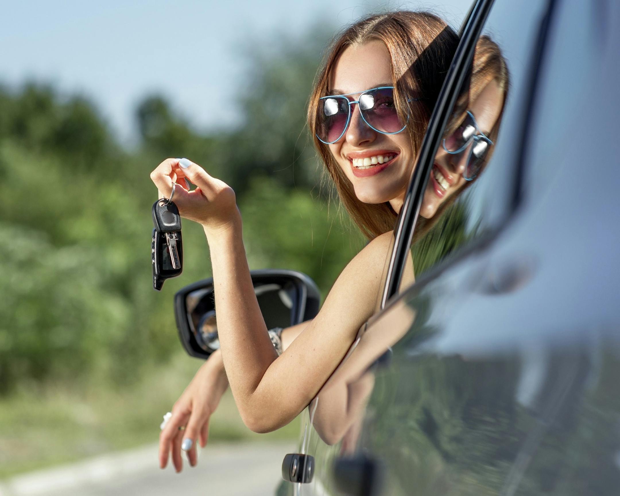 Car driver woman happy showing car keys out window