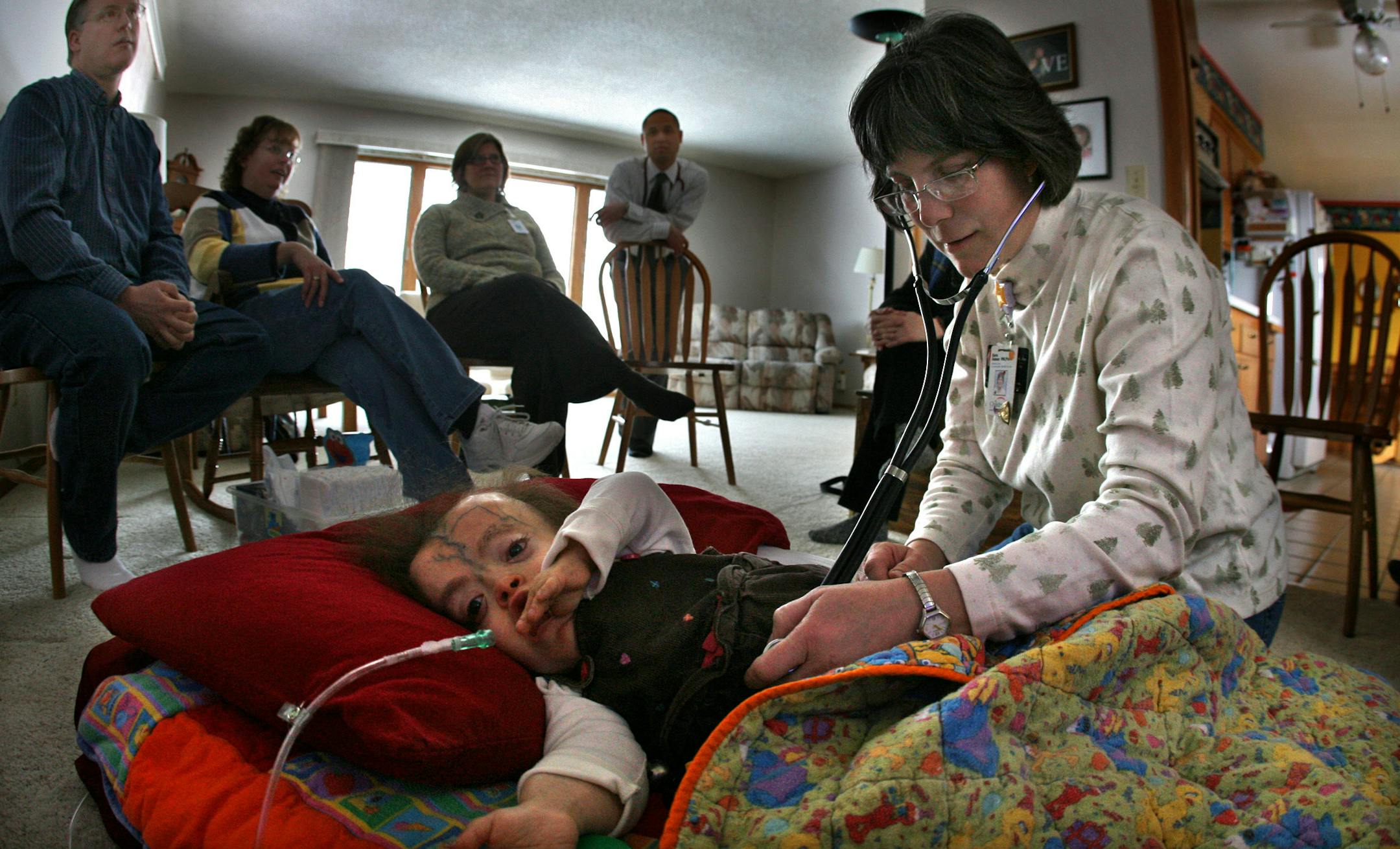 Parents Tom and Lisa Kimlinger (left) and palliative care specialists gathered around 11-year-old Amber Kimlinger during a recent meeting in the family's home. Amber has a rare genetic disorder called Lenz-Majewski syndrome that causes dwarfism among other serious medical problems. The team helps her parents decide on appropriate treatment. The team included social worker Martha Schermer (third from left), Dr. Tula Top (standing), Jean Madser (second from right) and Sara Hasse.