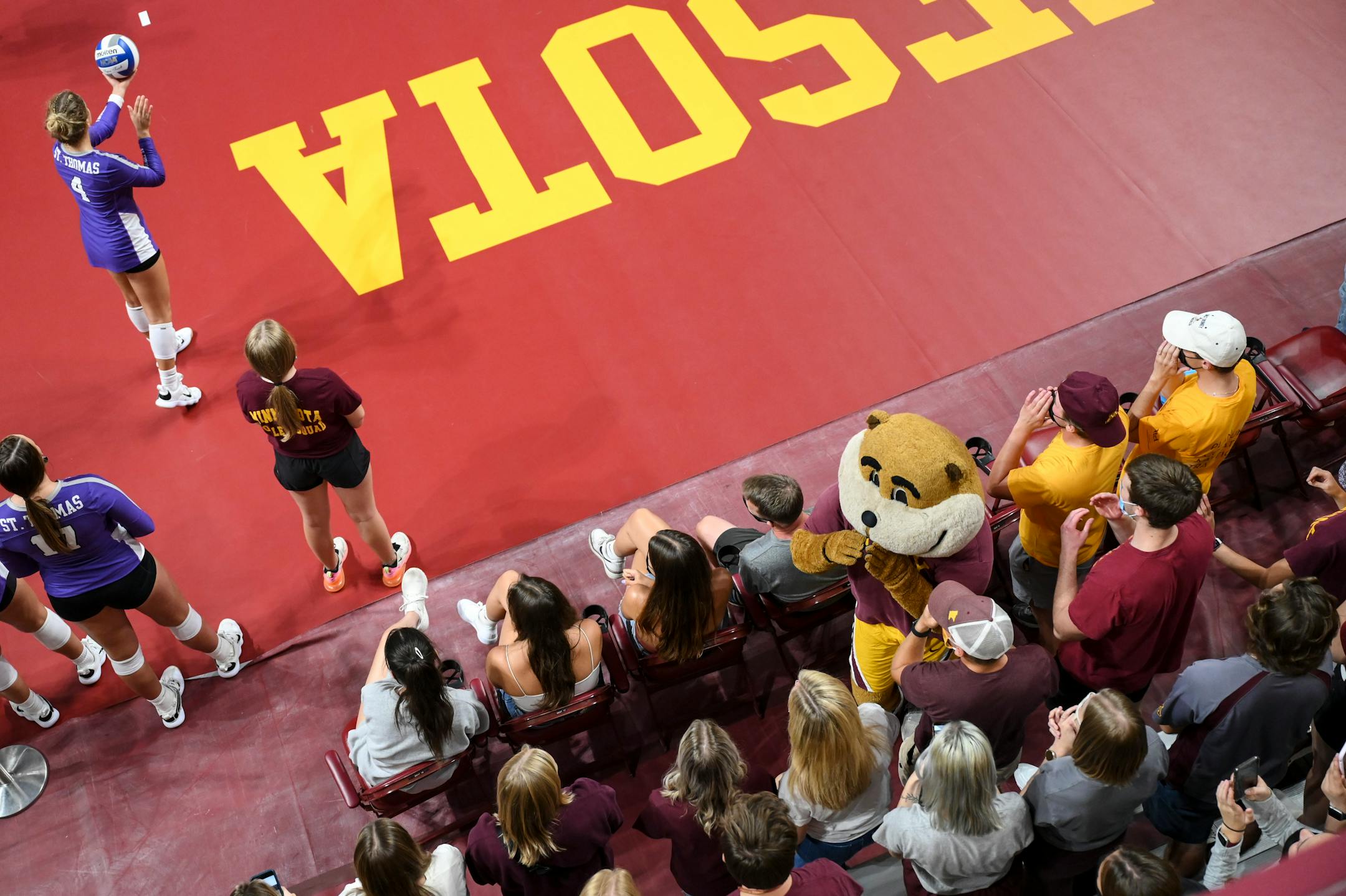 Goldy interacted with fans as St. Thomas defensive specialist Payton Willman (4) prepared to serve during the first set against the University of Minnesota Gophers.