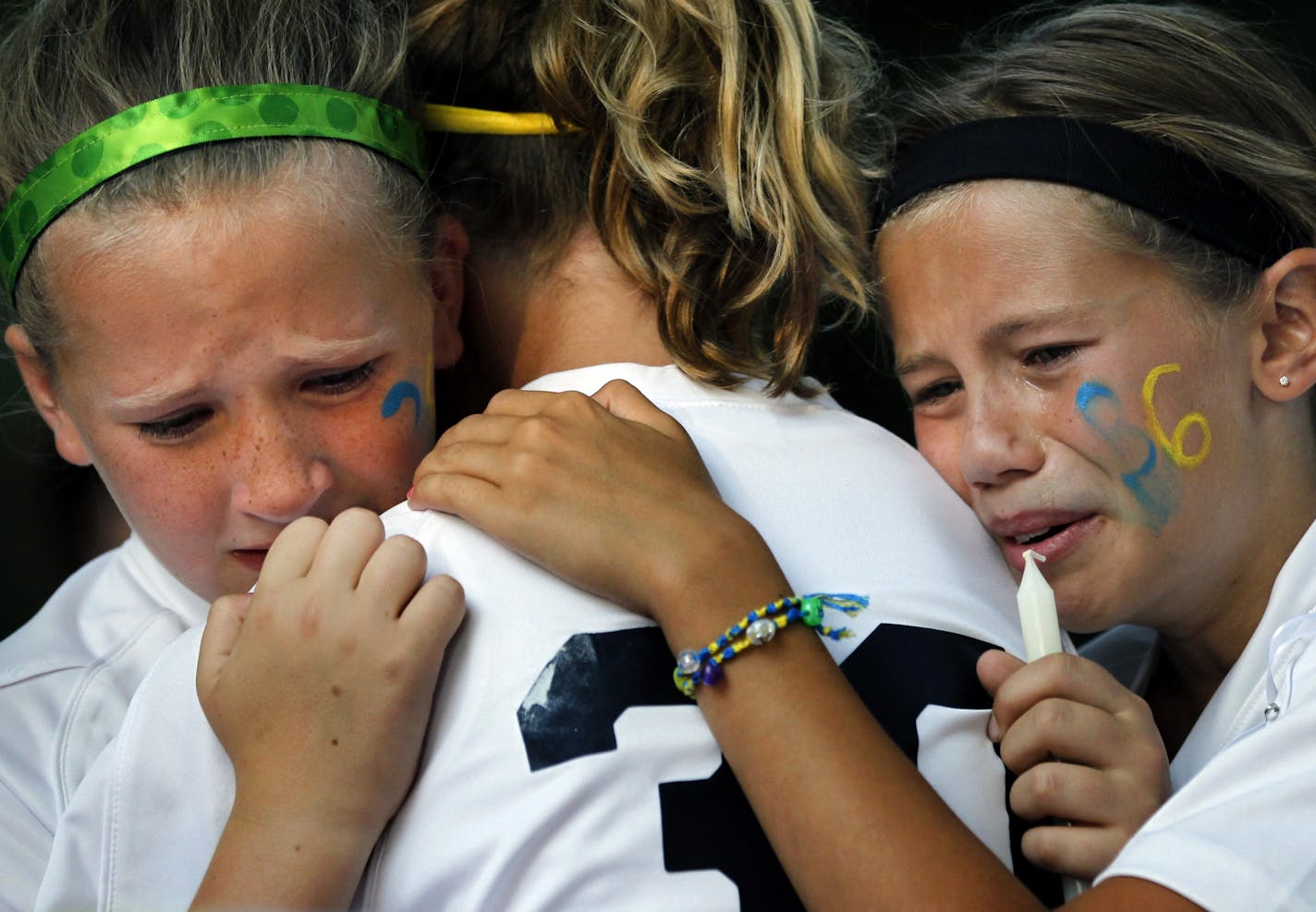 Faith Jensen, 11, (left) and Madyson Shew, 10, (right) hugged a teammate (center) during a vigil at Glen Park, for the three young sisters found dead in their home in River Falls, WI. The girls were soccer teammates of Amara Schaffhausen, 11.