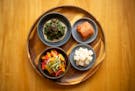 The banchans — mustard greens, napa kimchi, daikon kimchi and kabocha squash — at Kim's honor chef Ann Kim's Korean heritage and her Minnesota upb