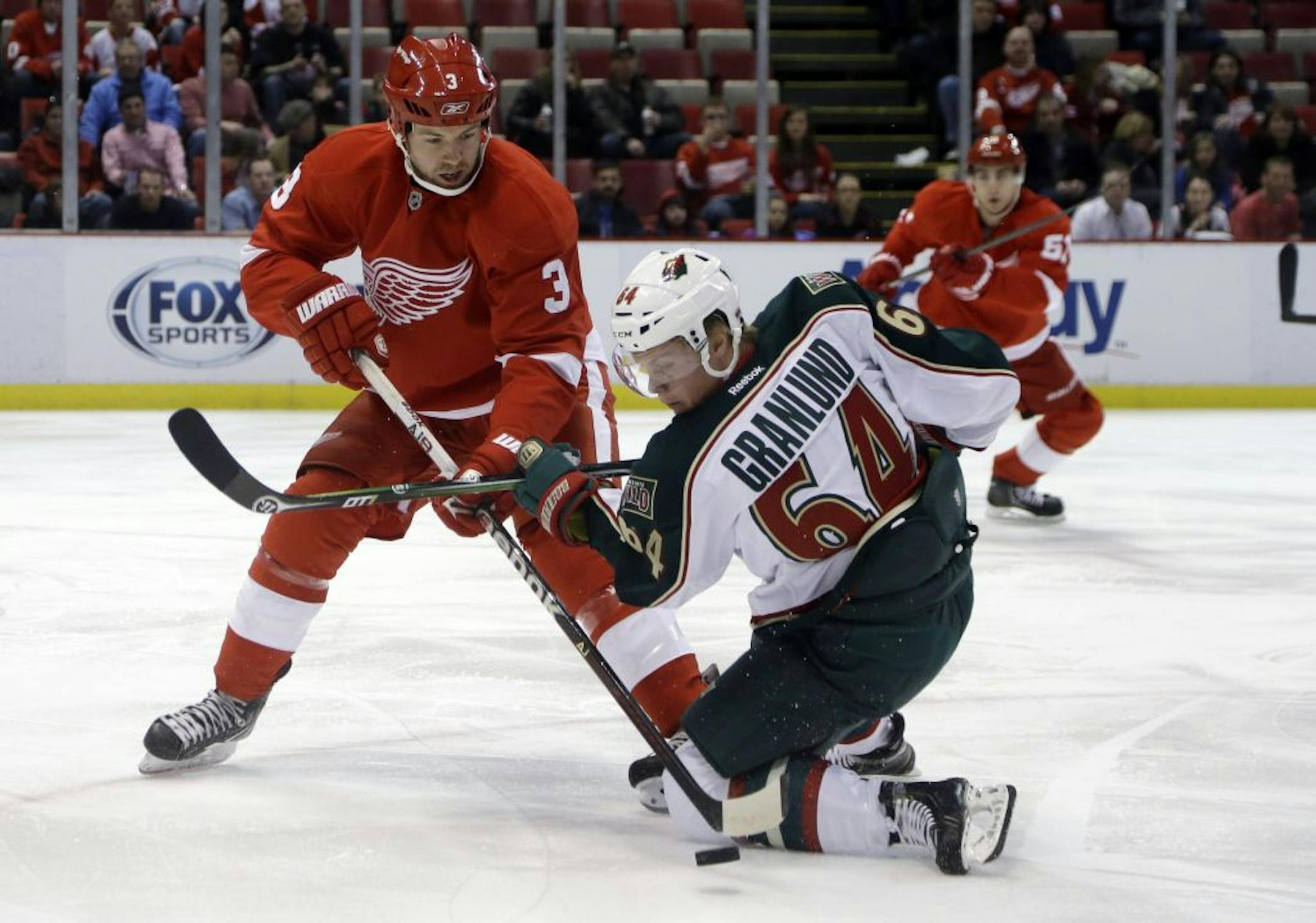 Detroit Red Wings defenseman Kent Huskins (3) and Minnesota Wild center Mikael Granlund (64), battle for the puck during the first period of an NHL hockey game in Detroit, Jan. 25, 2013.