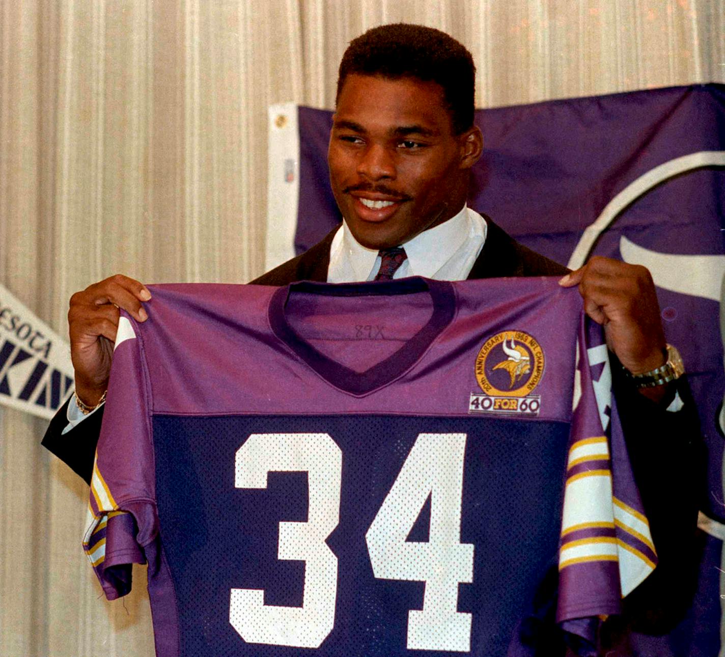 Herschel Walker holding up his new jersey after being traded to the Minnesota Vikings, during a new conference in Bloomington in October 1989.