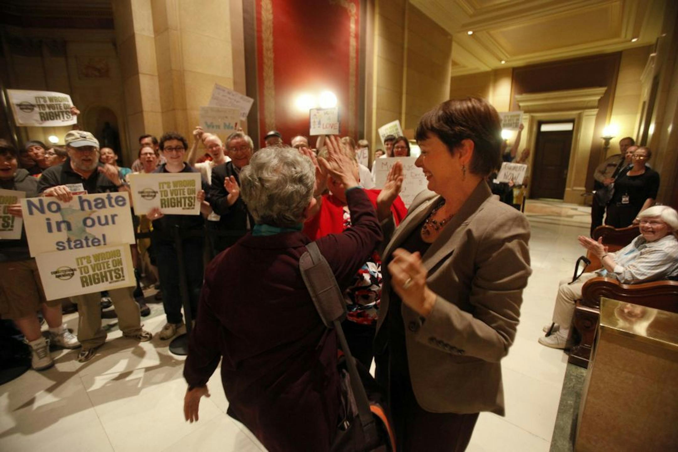 DFL representative Phyllis Kahn, left to right, and DFL senators Linda Higgins and Sandy Pappas high five one another in support of protestors of the constitutional ammendment against gay marriage outside the House chambers during the evening session.