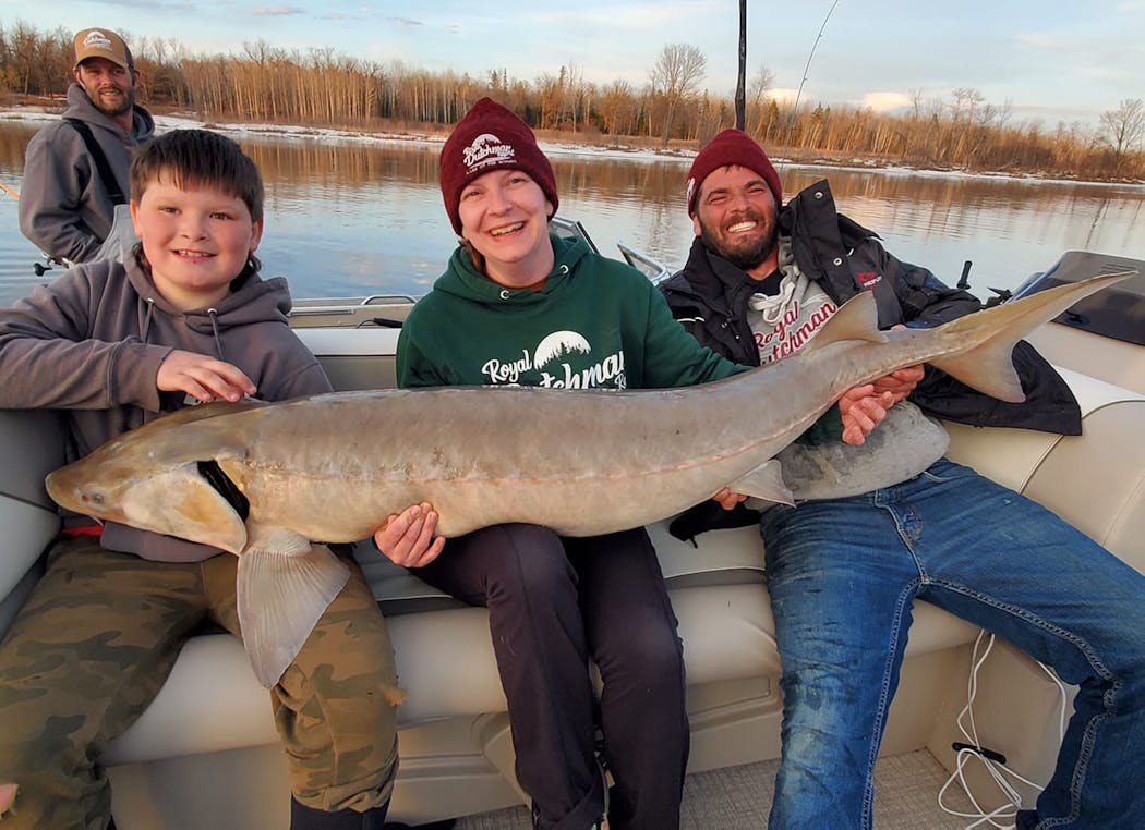 Jenn Hinrichs, center, with her personal best 63 1/2-inch sturgeon, caught in April. She was with son Jeffrey, left, and husband Kevin.