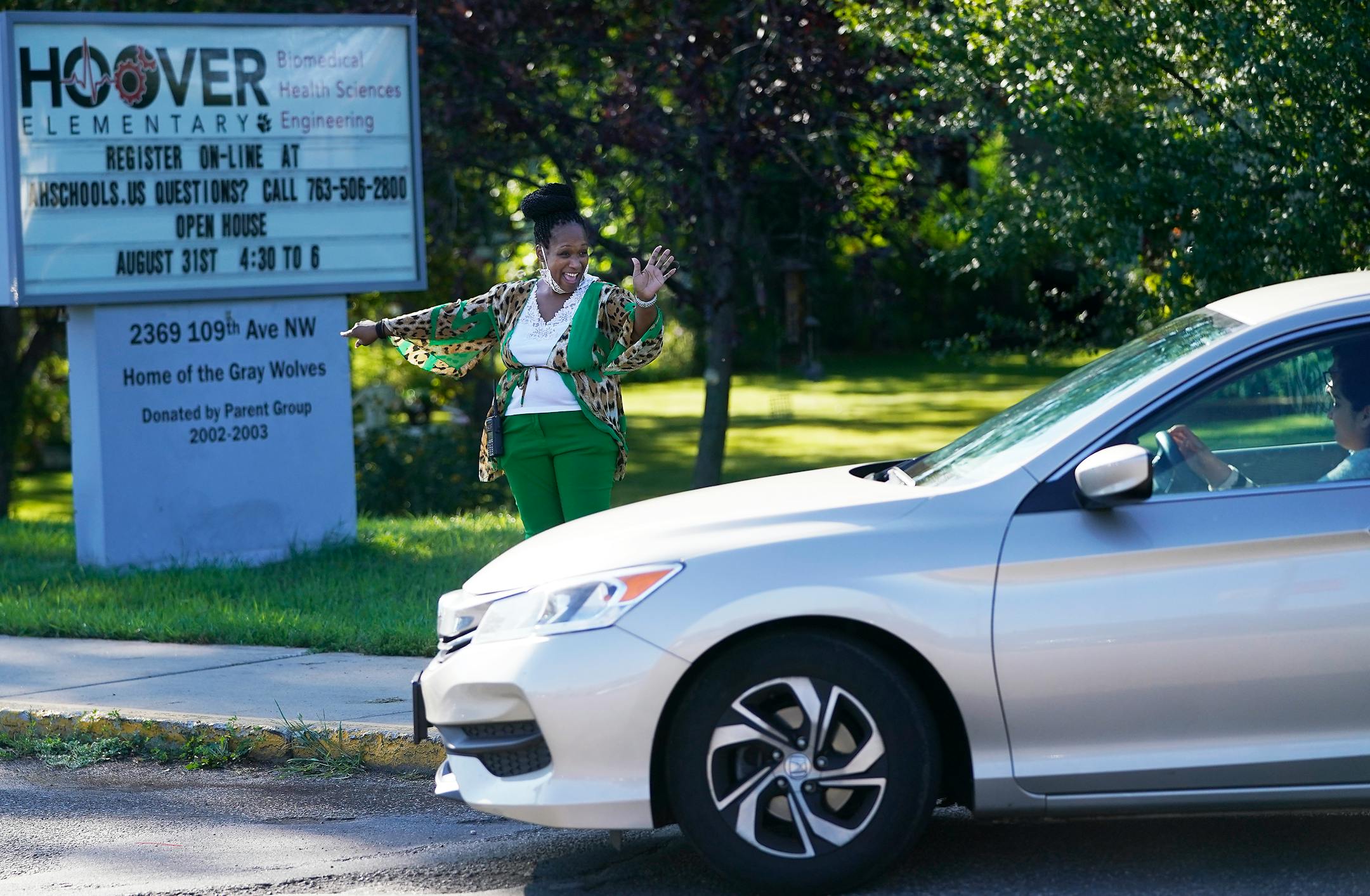 New Hoover Elementary School principal Keisha Davis waved at an arriving student and parent while directing traffic in the parking lot before the start of the first day of school Tuesday in Coon Rapids.   ]