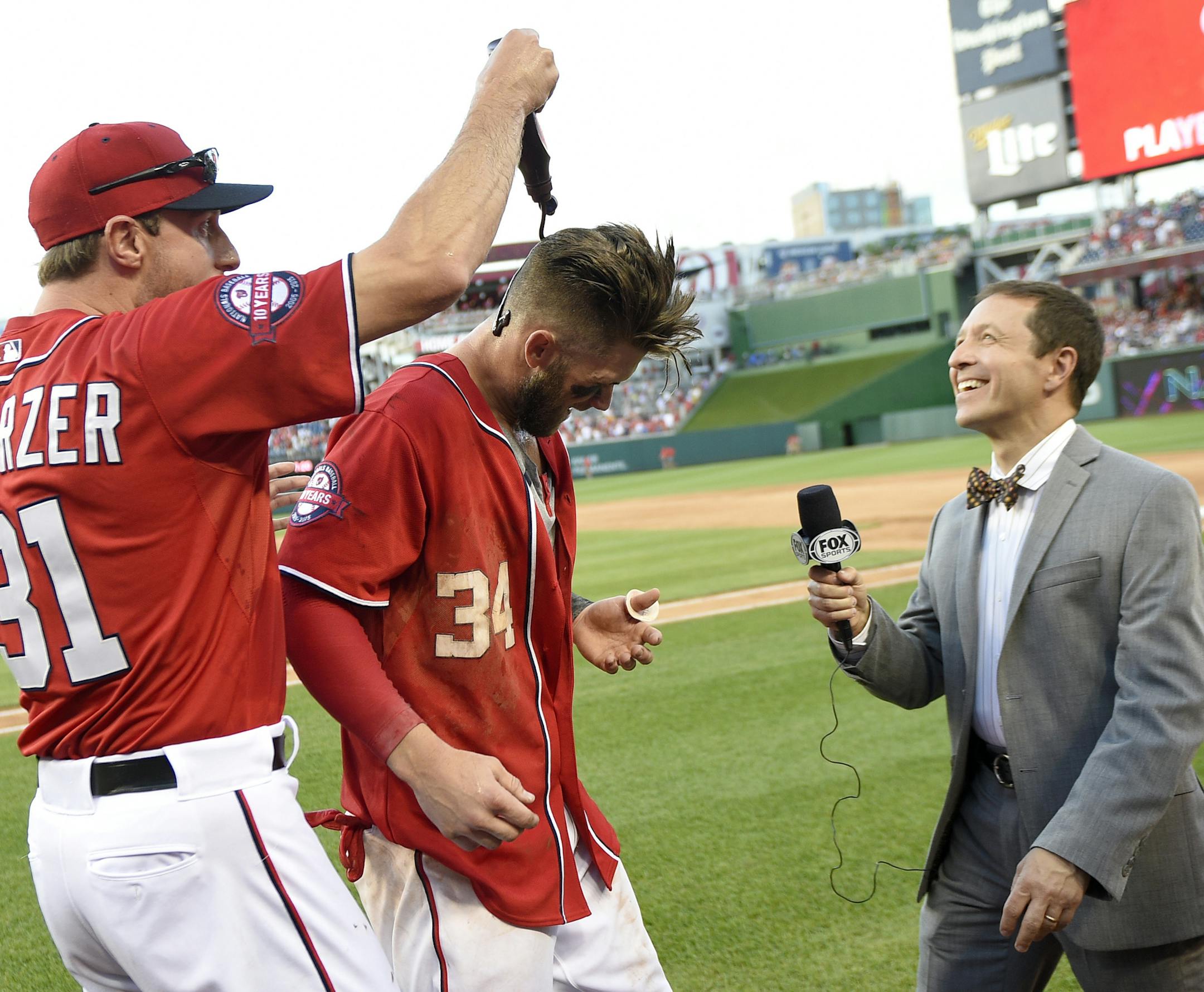 Washington Nationals' Bryce Harper, center, has chocolate sauce poured on him by teammate Max Scherzer, left, after Harper hit a two-run walk-off home run in the ninth inning of a baseball game against the Atlanta Braves to end the game, Saturday, May 9, 2015, in Washington. The Nationals won 8-6. (AP Photo/Nick Wass)
