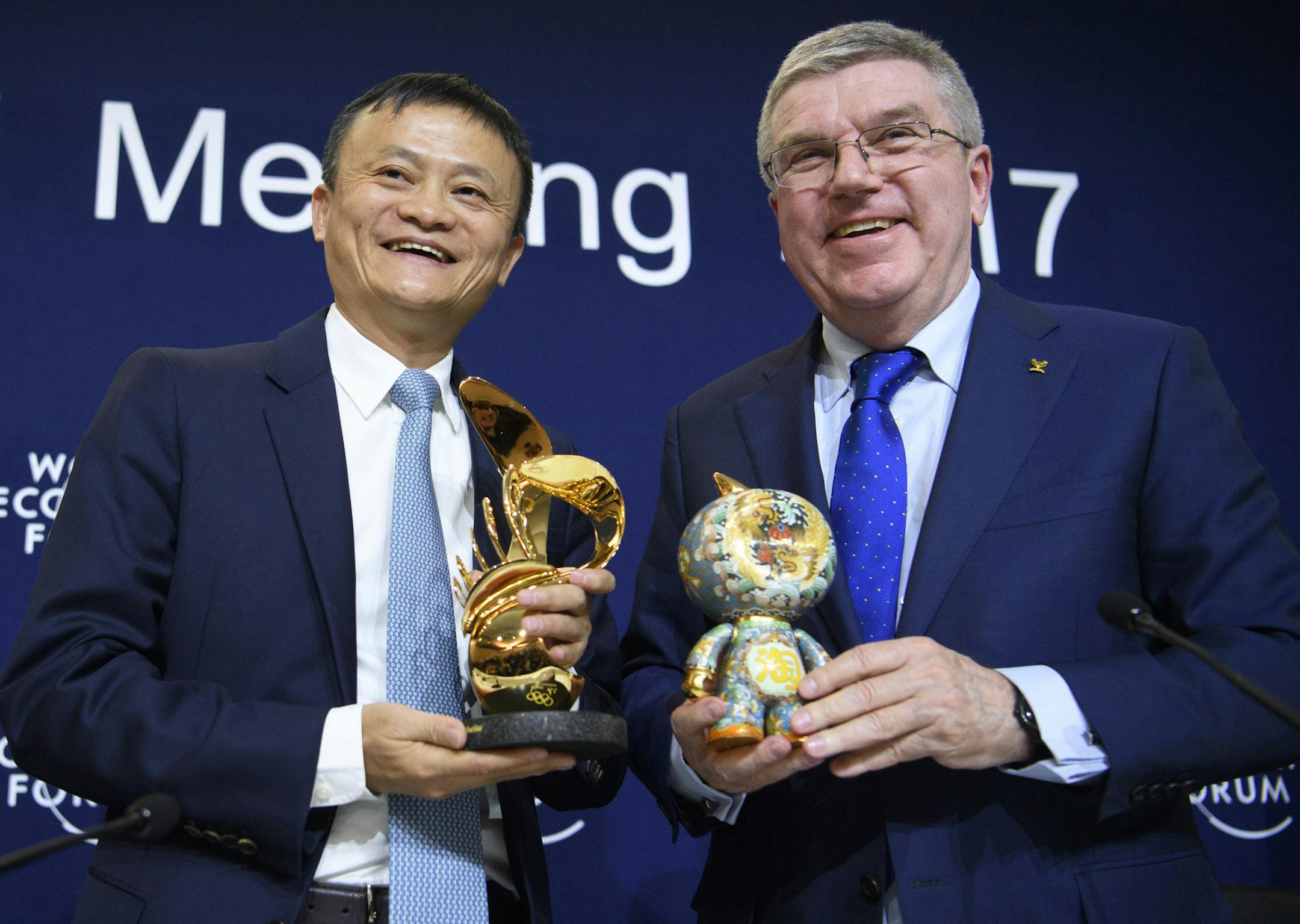 International Olympic Committee (IOC) president Thomas Bach, right, from Germany exchanges gifts with China's Jack Ma, left, Founder and Executive Chairman of Alibaba Group during a press conference at the 47th annual meeting of the World Economic Forum, WEF, in Davos, Switzerland, Thursday, Jan. 19, 2017. (Laurent Gillieron/Keystone via AP) ORG XMIT: FOS123