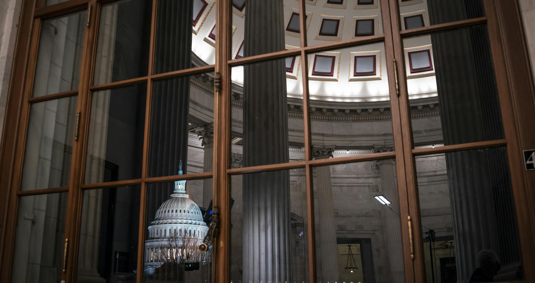 The Capitol is seen amid reflections of the Russell Senate Office Building as the impeachment trial of President Donald Trump on charges of abuse of power and obstruction of Congress, stretches into the night, in Washington, Wednesday, Jan. 29, 2020. (AP Photo/J. Scott Applewhite)