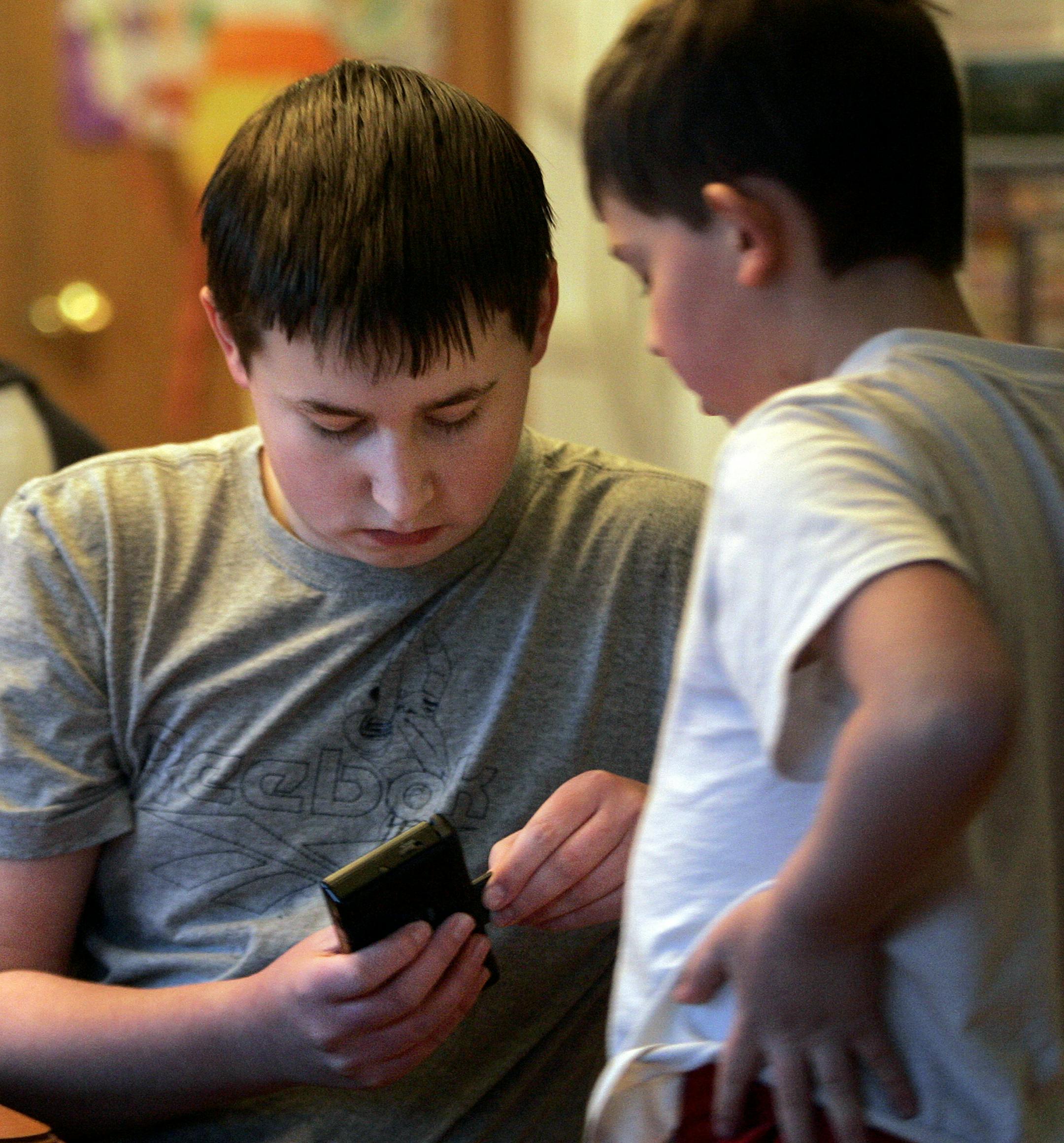 Luke Schneider, 14, helped his brother Jacob Schneider, 9, with a video game at their Brooklyn Park home Friday, Jan. 2, 2008. Luke is in his first year of taking school classes online from home, which allows him to help care for Jacob, who has autism.
