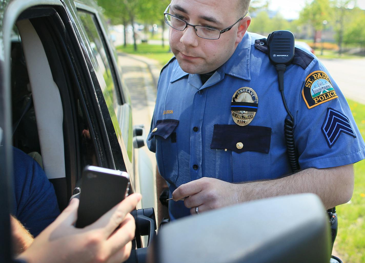 St. Paul police officer Jeremy Ellison looked at what a driver admitted to viewing on his cell phone while he was at a traffic light on Lexington Avenue on Wednesday, April 25, 2012 in St. Paul, Minn. after getting pulled over as law enforcement steps up enforcement of distracted driving, sometimes more easily spottable for officers at traffic lights. ] (RENEE JONES SCHNEIDER/ reneejones@startribune.com) Jeremy Ellison ORG XMIT: MIN2014072411030820