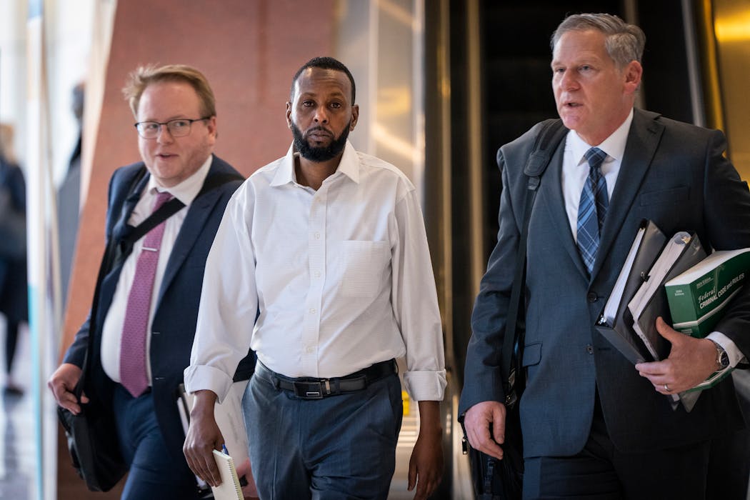 Defendant Said Shafii Farah, center, walks into the United States District Court with his attorneys Clayton Carlson, left, and Steve Schleicher during the first day of jury selection in the first Feeding Our Future case to go to trial in Minneapolis on April 22.