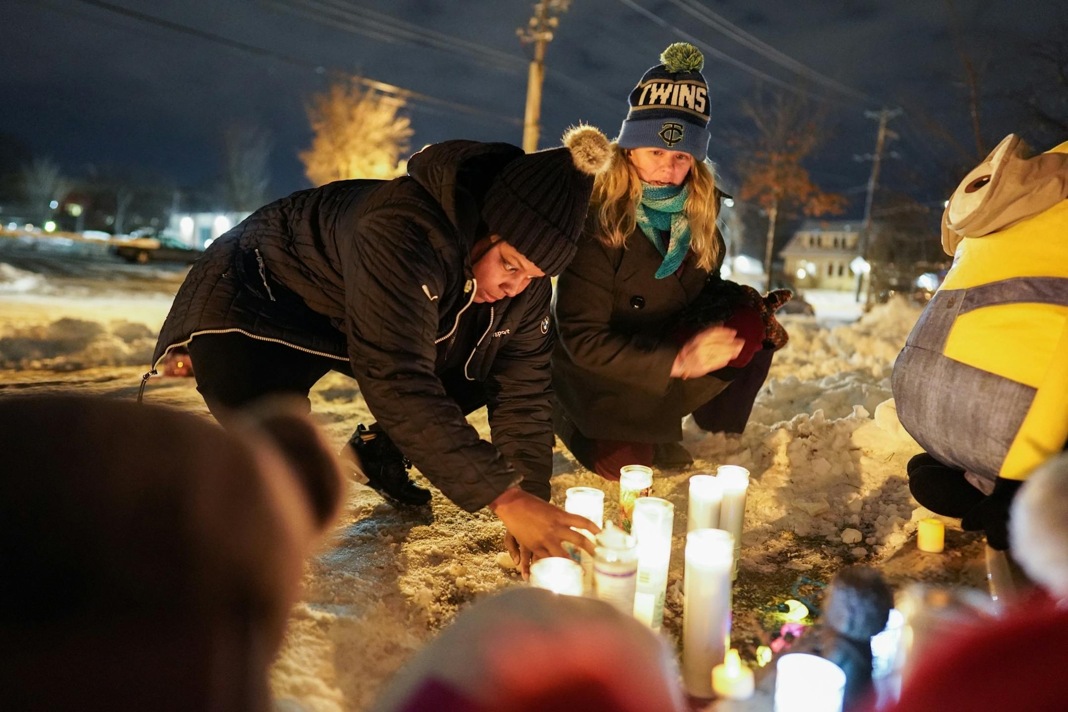 Alicia Smith and Christine Lorenz tended to candles lit at the vigil for members of the Schladetzky family on Oakland Avenue S. Smith's children played football with the Schladetzky boys.