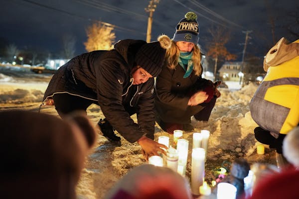 Alicia Smith and Christine Lorenz tended to candles lit at the vigil for members of the Schladetzky family on Oakland Avenue S. Smith's children playe