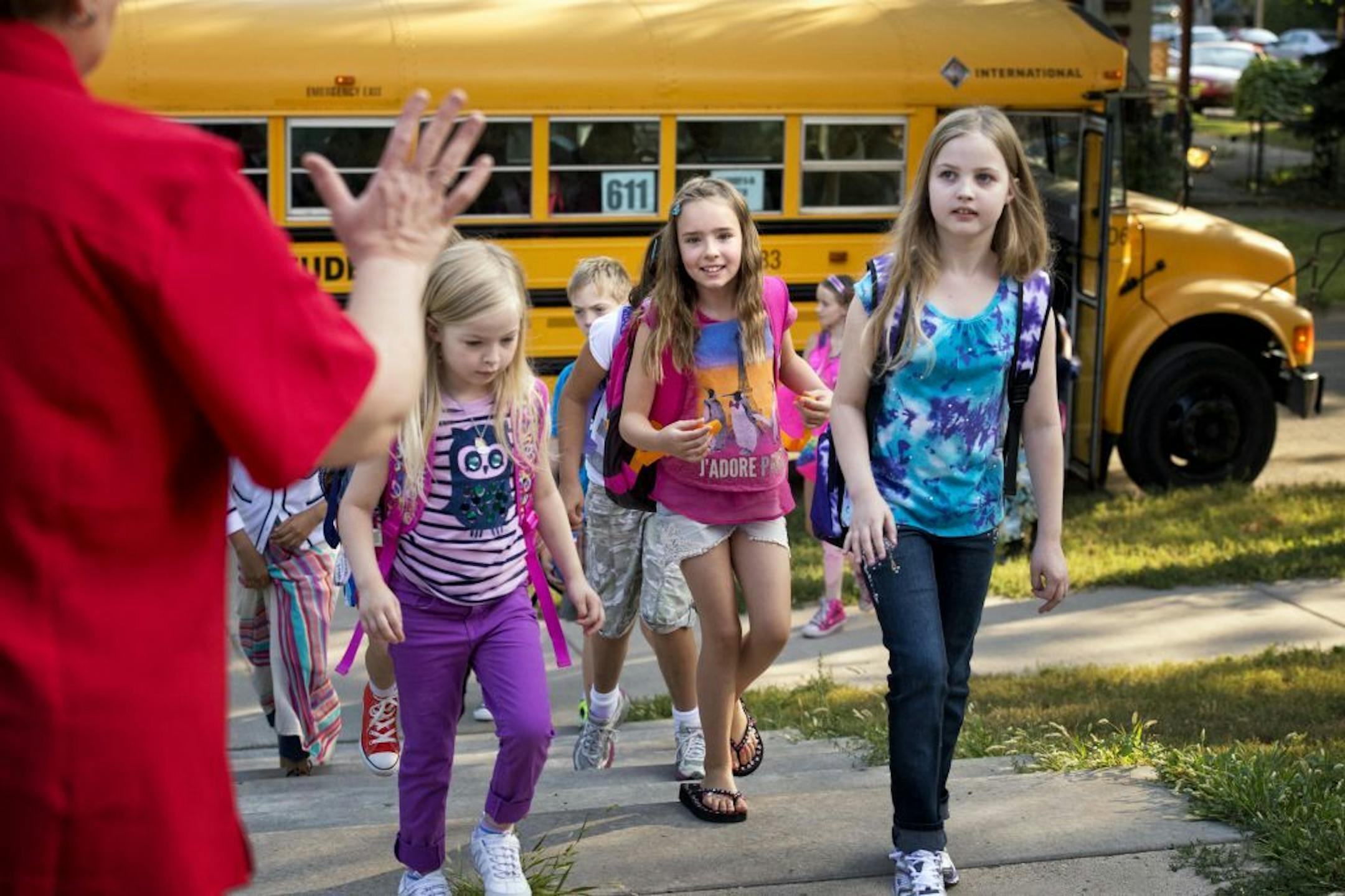 Marcy Open School principal Donna Andrews greeted students Maya Jacobson, Savana Gartner and Aurora Jacobson as they got off the bus for the first day of classes in Minneapolis on August 26.