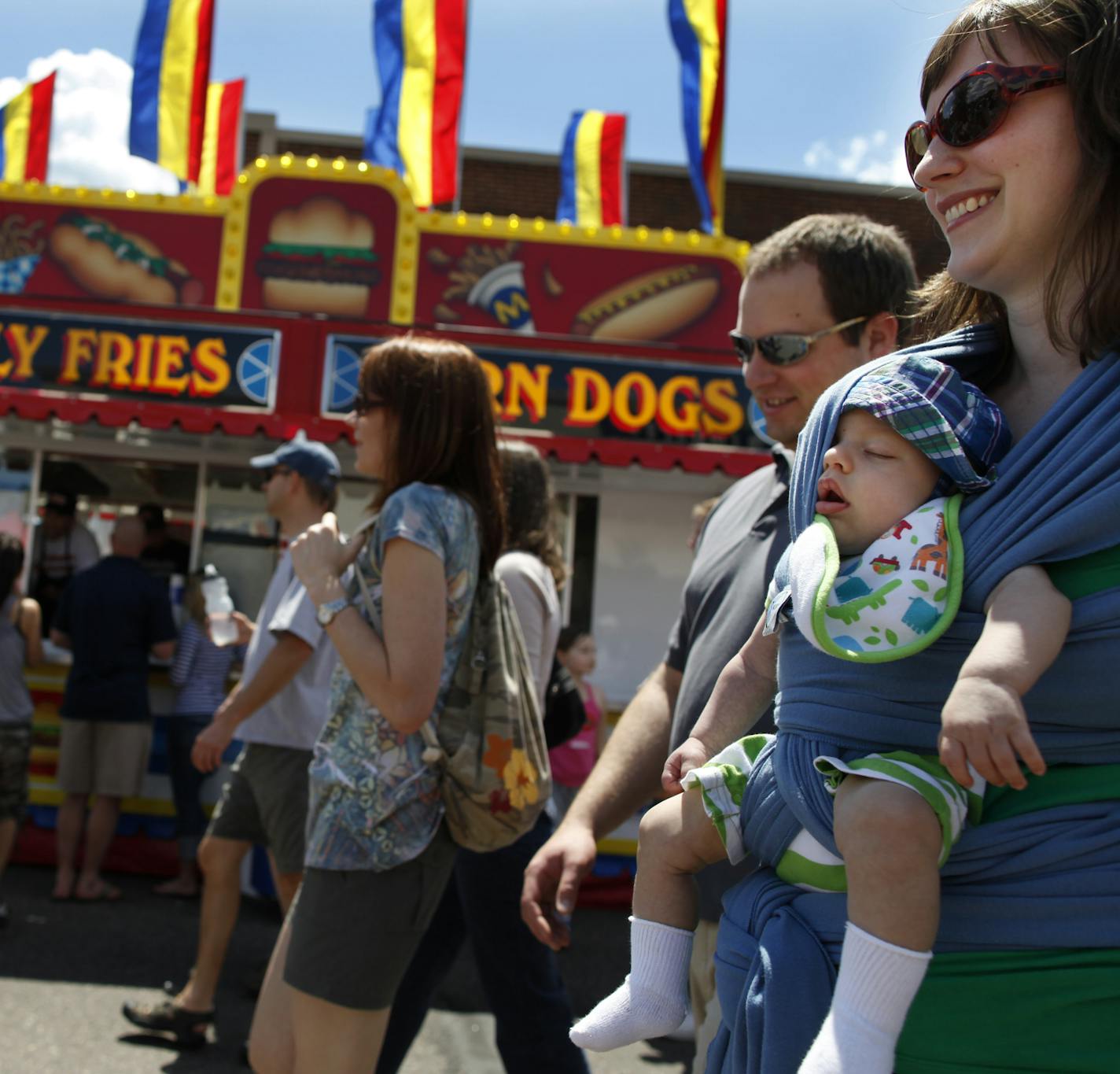 Richard Tsong-Taatarii/rtsong-taatarii@startribune.com St. Paul, MN;6/6/10;left to right ] At the Grand Old Day celebration which takes place on the first Sunday of June, St. Paul resident Solomon Rinehart, three and a half months old, did not wake up to the smells of curly fries and corn dogs while carried by his mother, Andrea and accompanied by dad, Nate, second from right. "It's perfect weather. Not too hot," said Andrea.