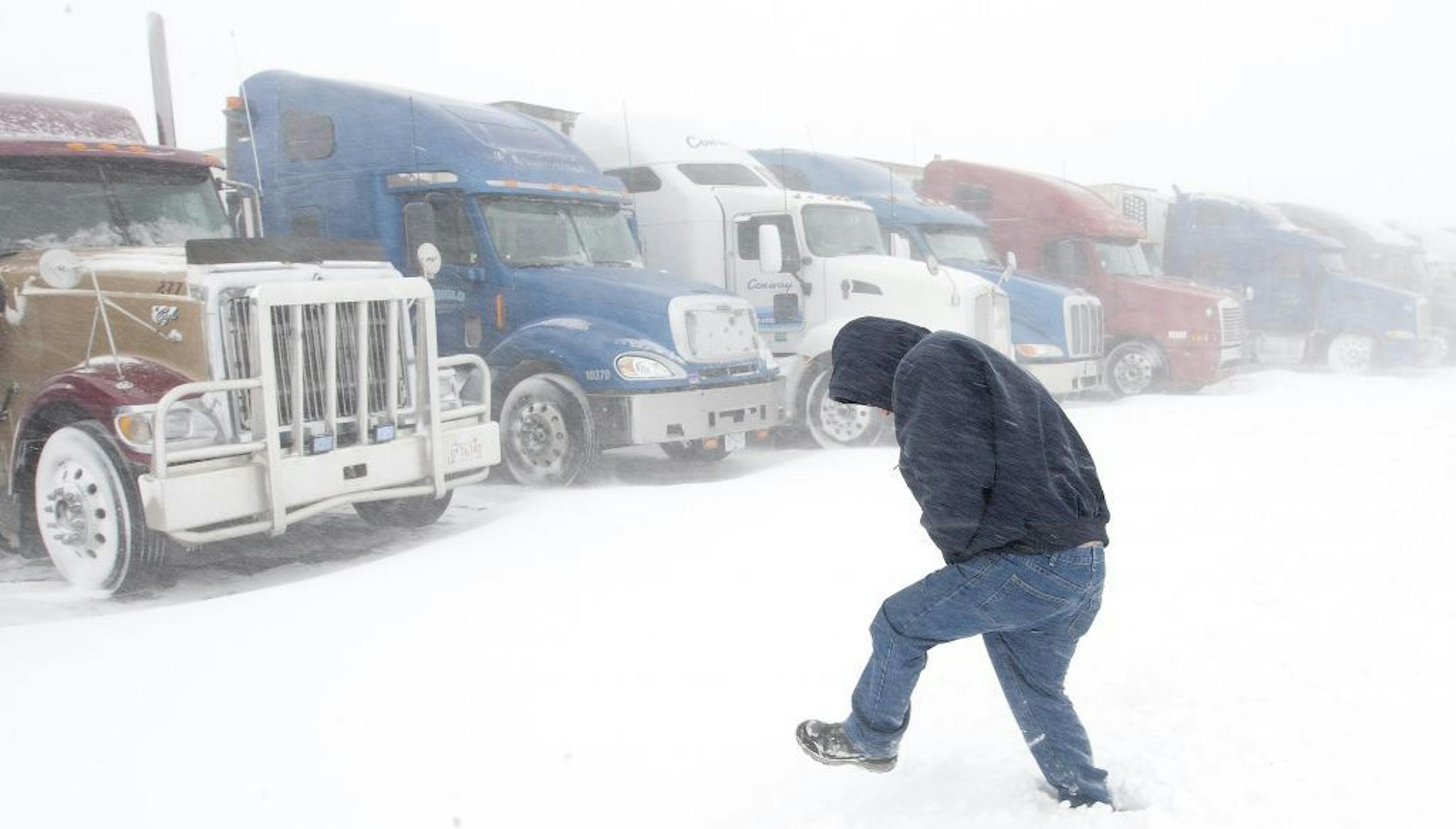Wes Bevans, a truck driver from Northern California, walks to his truck at the Flying J Travel Plaza in Grand Forks, N.D., Monday. Dozens of semi trucks were forced to wait out the storm as Interstate 29 from Grand Forks to the Canadian border closed.
