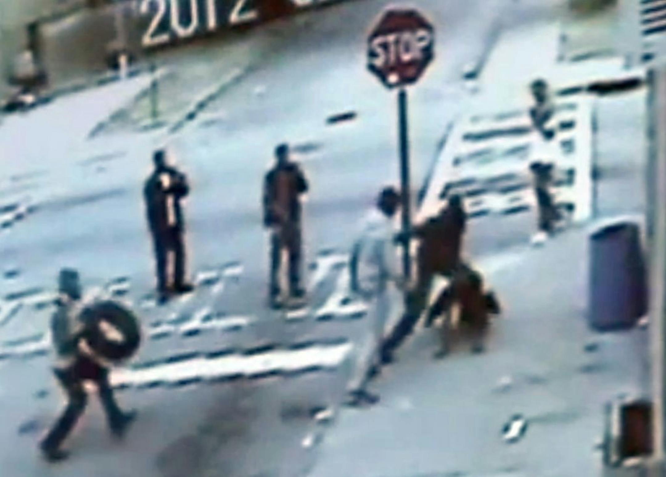 This frame-grab from a store surveillance camera shows people making videos during the gang beating in the Pittsburgh neighborhood of Atlanta. Federal authorities have said they are investigating the Feb. 4 attack as a possible hate crime. The video shows three unidentified men pouncing on Brandon White as he walks out of a grocery store in the city's Pittsburgh neighborhood south of downtown. They punch and kick him while gay slurs are heard. At one point, an attacker slams a tire onto White's
