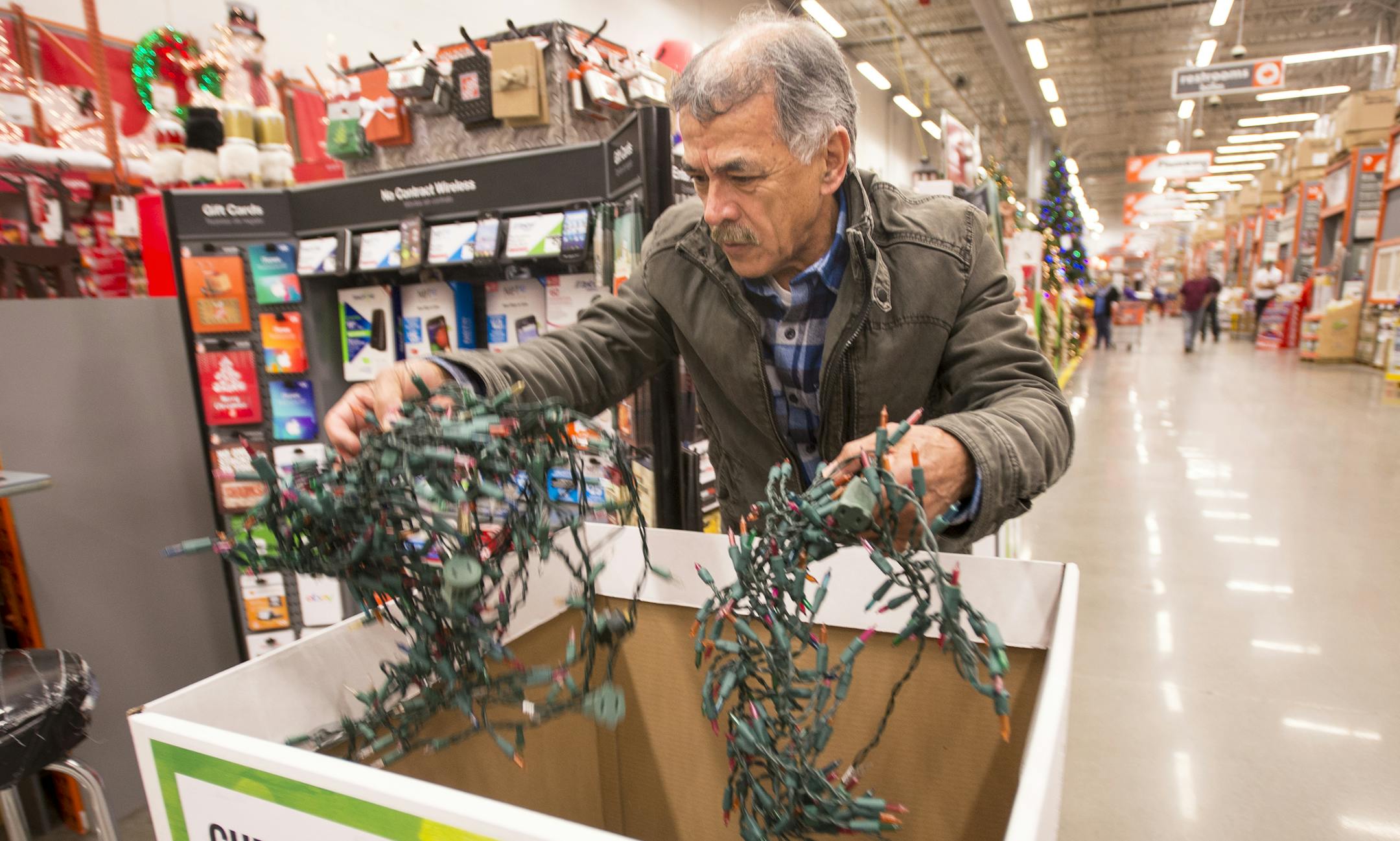 Dario Morales, of Crystal, untangled some of the lights he traded in on Friday for new LED lights. He hoped to take advantage of the unseasonably warm weather this weekend to hang lights with his family. ] (AARON LAVINSKY/STAR TRIBUNE) aaron.lavinsky@startribune.com Nice weather may make this the weekend to bring out the holiday lights and test which strands have burnt out or become unbearably tangled. Rather than tossing them in the trash, Home Depot and some other retailers and facilities will